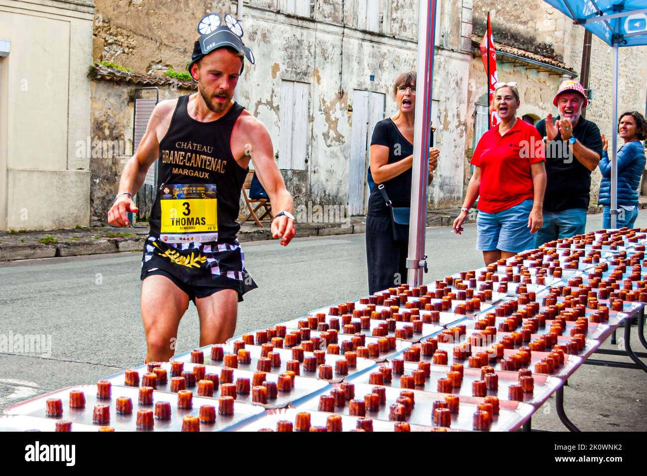 Al grande applauso degli assistenti di stand, un primo corridore afferra e si serve per un totale di 4.000 caneelés, che il dipartimento Gironde ha preparato per i partecipanti. Lesparre-Médoc, Francia Foto Stock