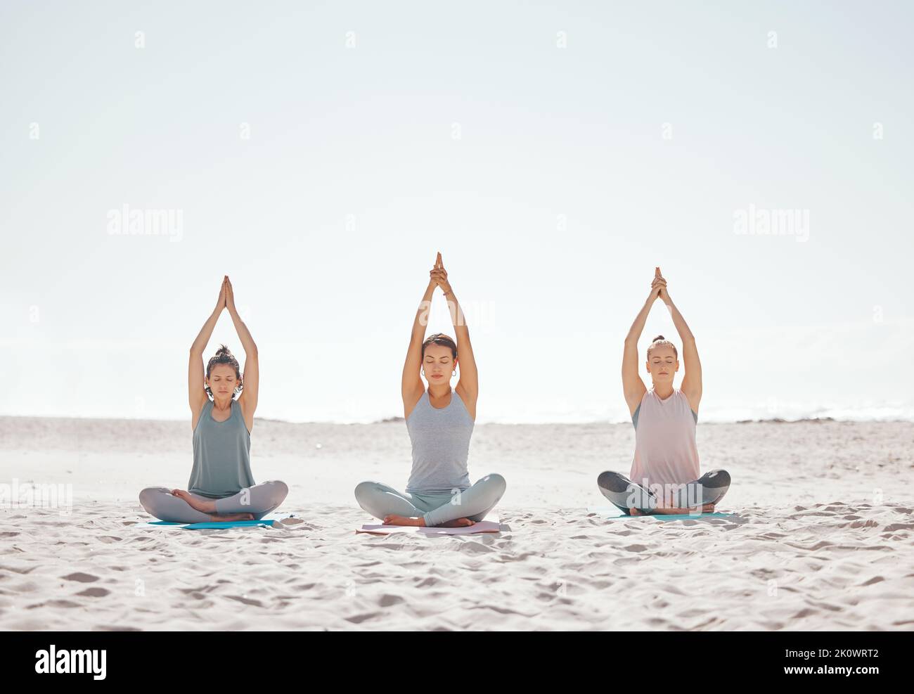 Zen, meditazione e yoga in spiaggia con donne per il benessere, fitness e salute. Stretching, lotus posa e amici che fanno un pilates allenamento o. Foto Stock