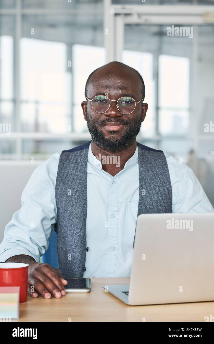 Giovane lavoratore di successo nell'abbigliamento da ufficio seduto sul posto di lavoro di fronte al computer portatile e preparando il progetto o la presentazione per la conferenza Foto Stock