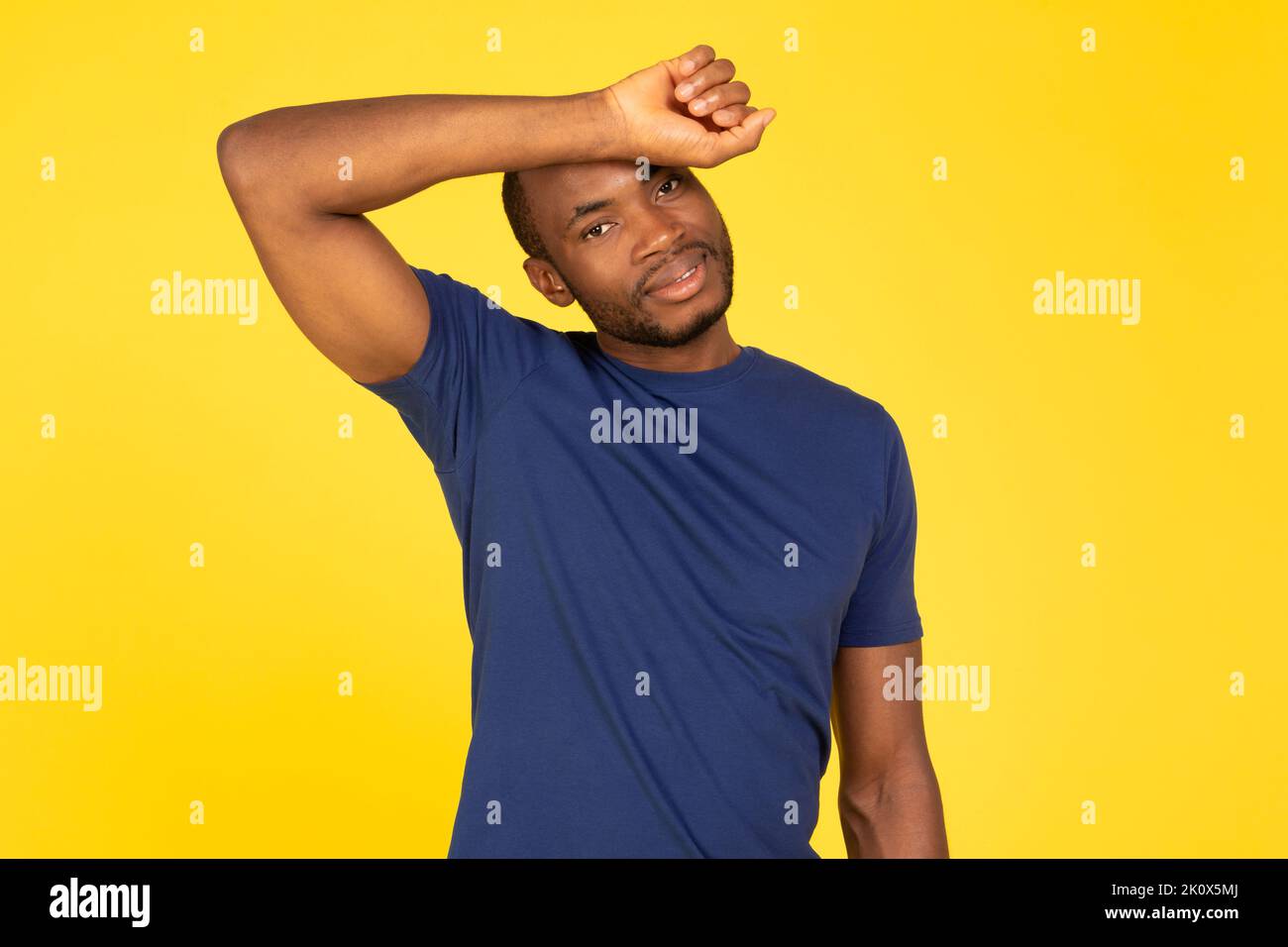 Uomo afroamericano sportivo che puliscono il sudore dalla fronte, sfondo giallo Foto Stock
