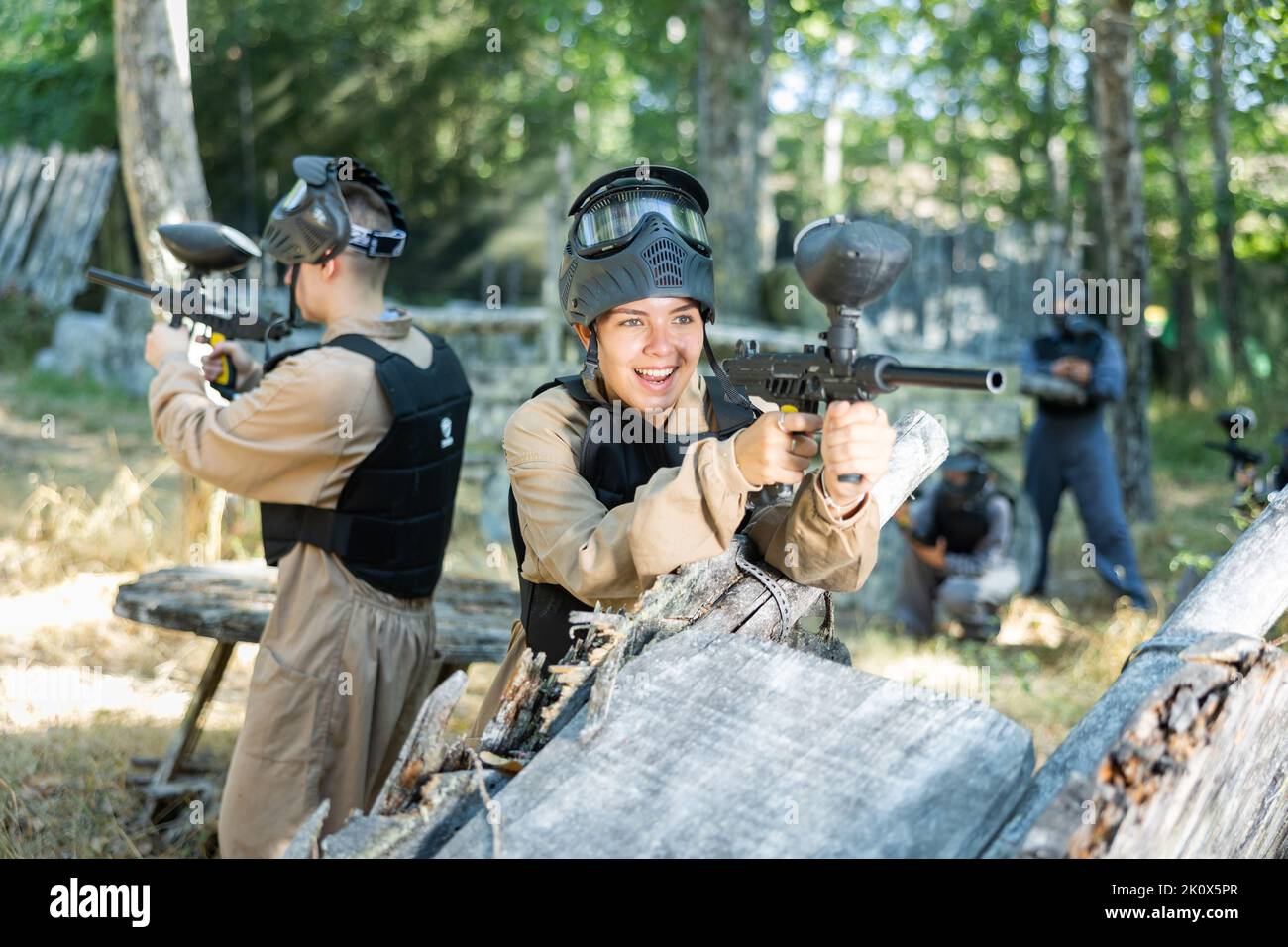 La donna spara una pistola con passione mentre gioca paintball Foto Stock
