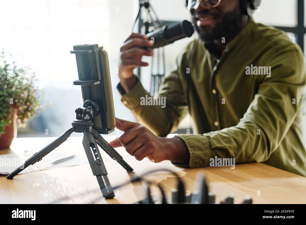 Mano di giovane afro-americano blogger maschio toccare lo schermo dello smartphone mentre inizia la registrazione di nuovo file video per il pubblico online Foto Stock