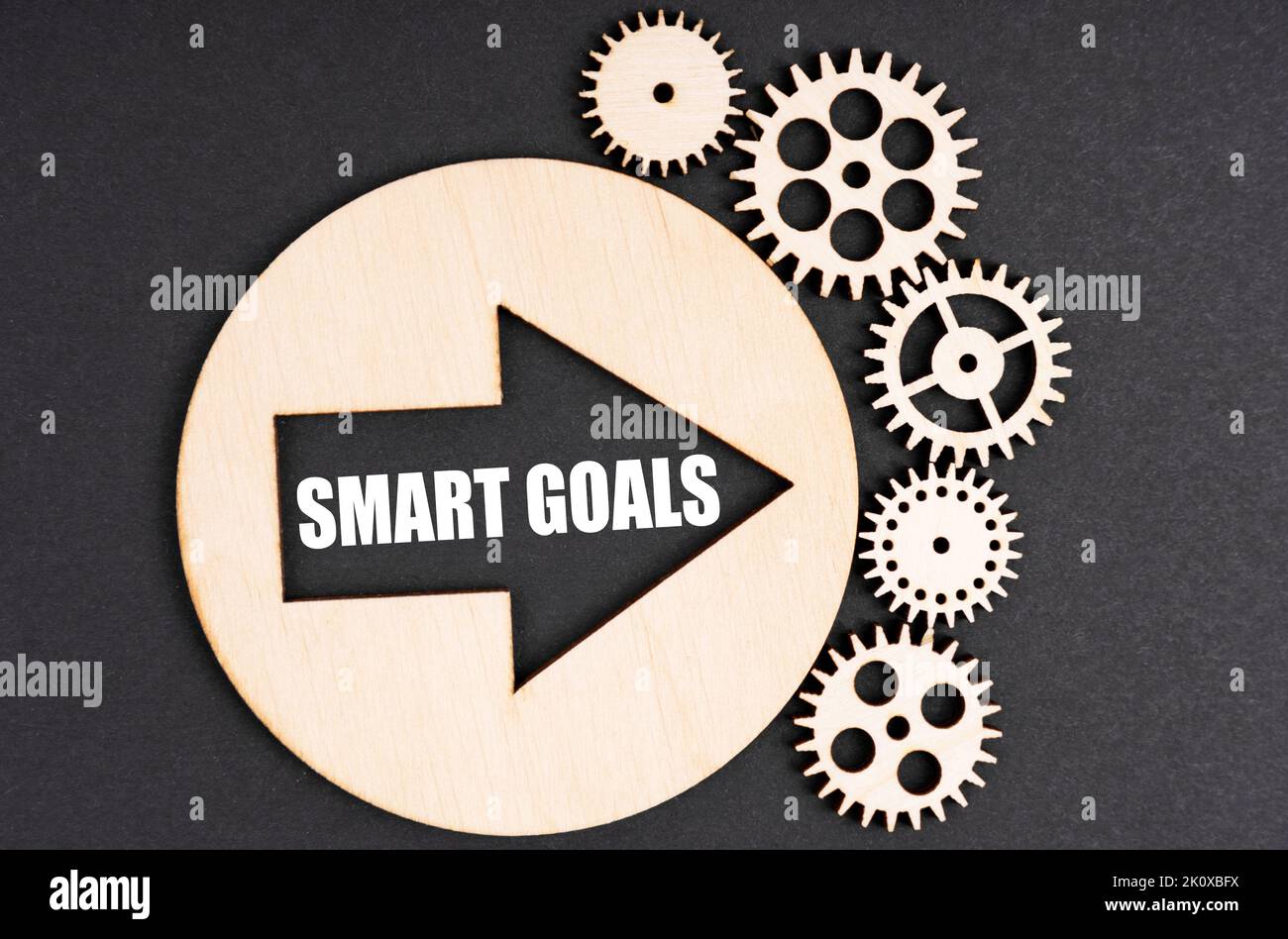Concetto di business e finanza. Su uno sfondo nero, ci sono ingranaggi di legno e un cerchio all'interno del quale è presente una freccia con l'iscrizione - Smart G Foto Stock