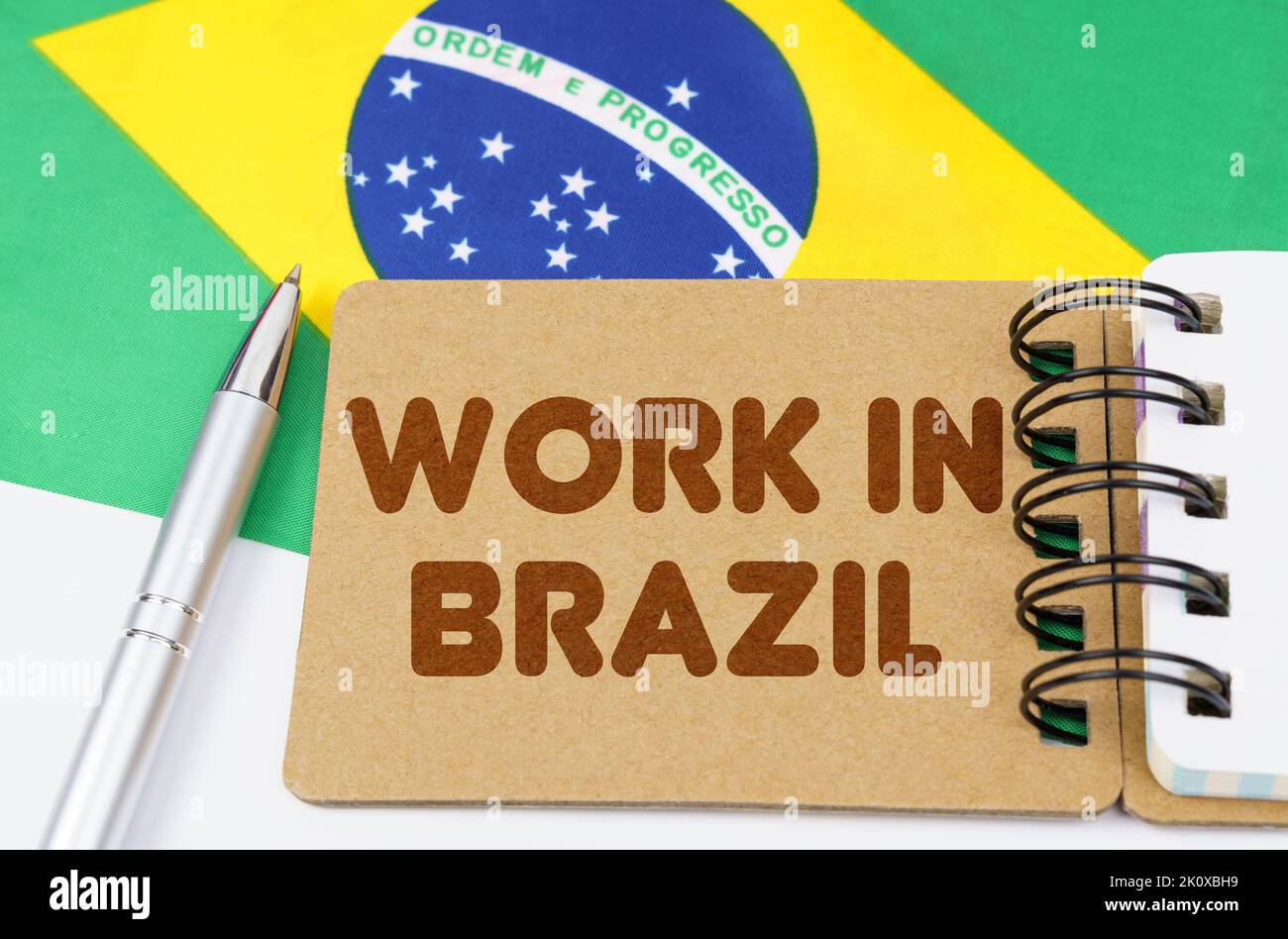 Concetto di economia nazionale. Sulla bandiera del Brasile si trova un notebook con l'iscrizione - lavoro in Brasile Foto Stock