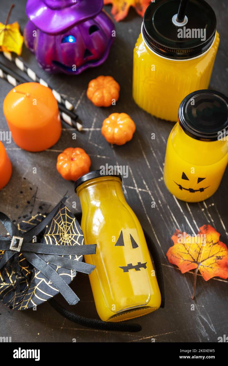 Halloween mocktail. Cocktail di zucca e limonata in vasetti di vetro decorati con facce spaventose e decorazioni su sfondo di pietra scura. Foto Stock