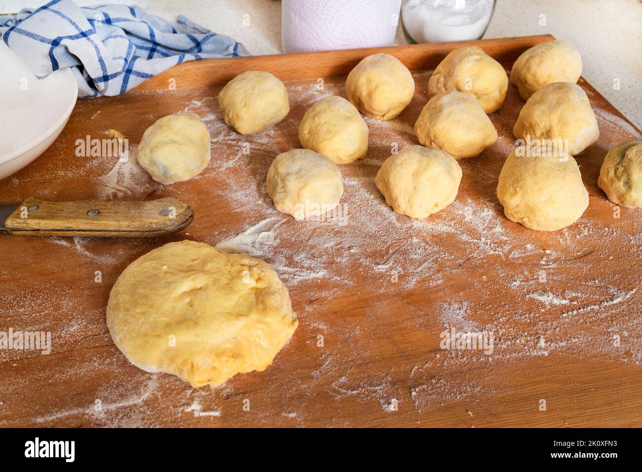Gnocchi di susina dolce e un pezzo di pasta di lievito. Preparazione di gnocchi di prugne su tavola da cucina in legno. Foto Stock