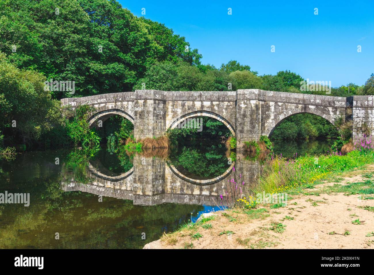 Ponte romano in Galizia riflesso in un fiume. Foto Stock