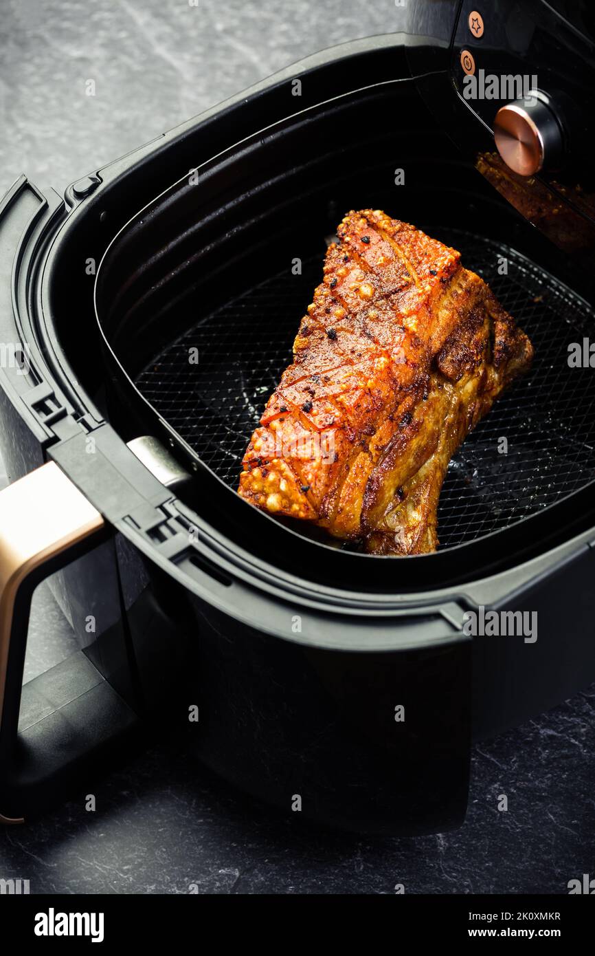 Cuoce croccante di maiale in airfryer. Cottura rapida e semplice di alimenti croccanti con poco o nessun grasso facendo circolare aria calda all'interno del cestello Foto Stock