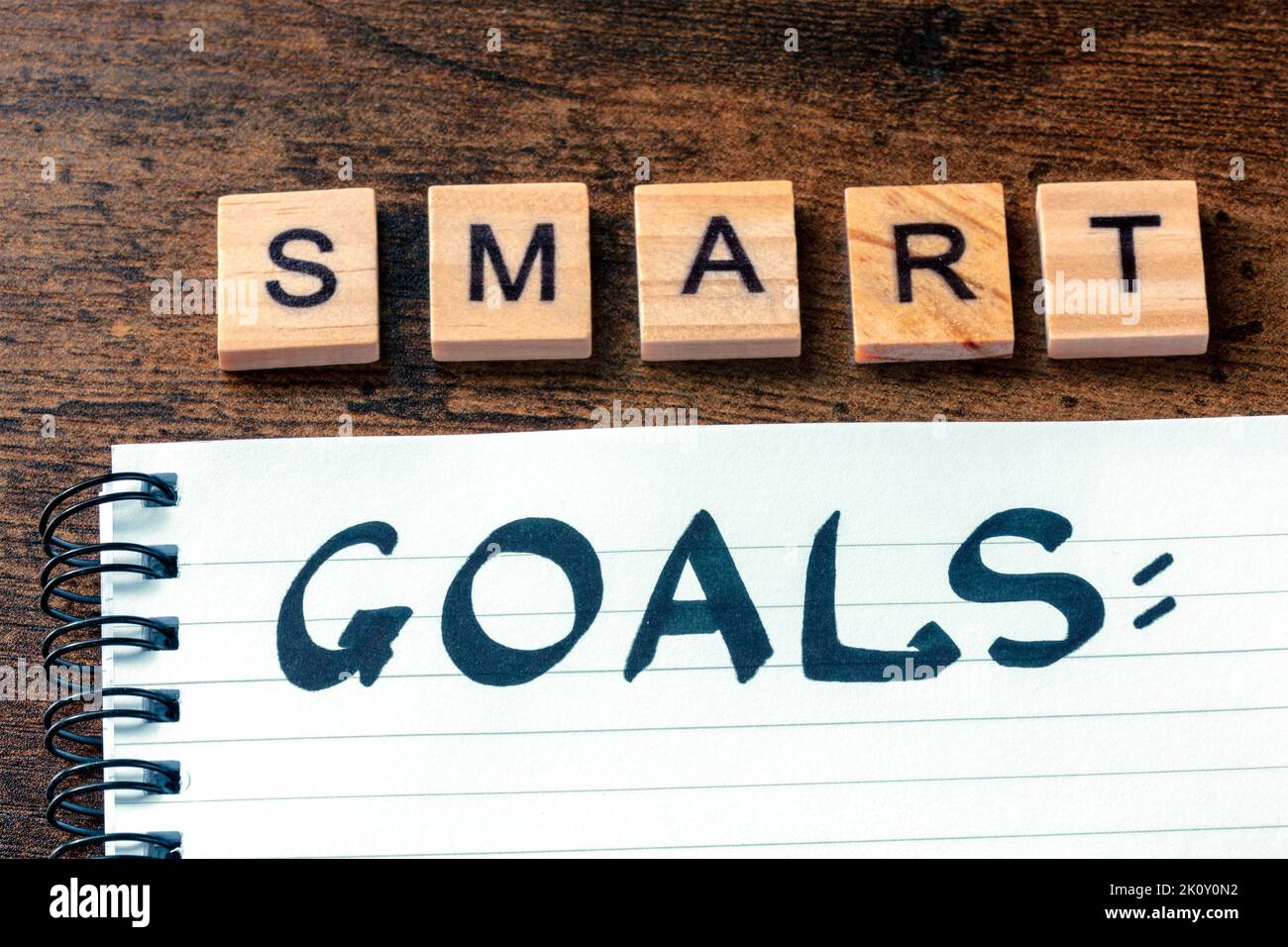 Concetto Smart Goals. La parola manoscritta in un blocco note su una scrivania di legno. Scrivere un piano o un elenco Foto Stock