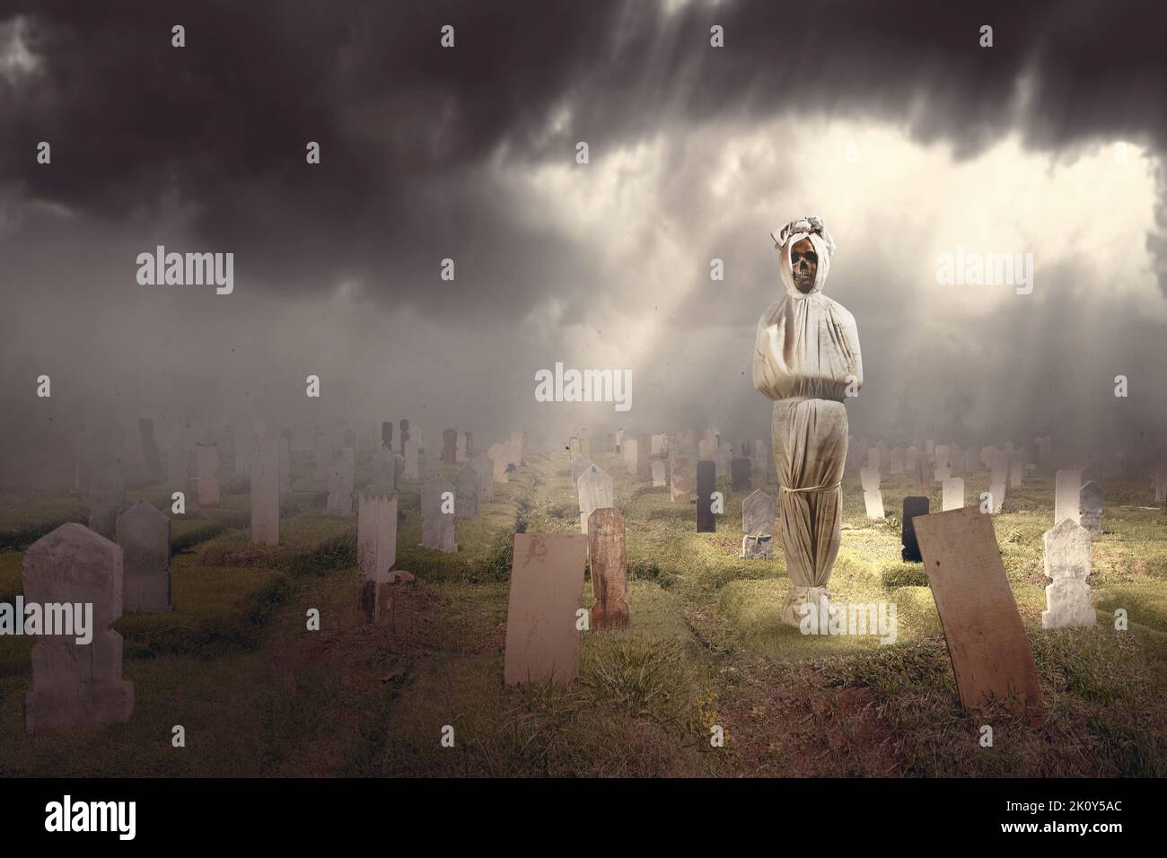 Pocong è coperto da una copertura di lino bianco in piedi nel cimitero. Concetto di Halloween Foto Stock