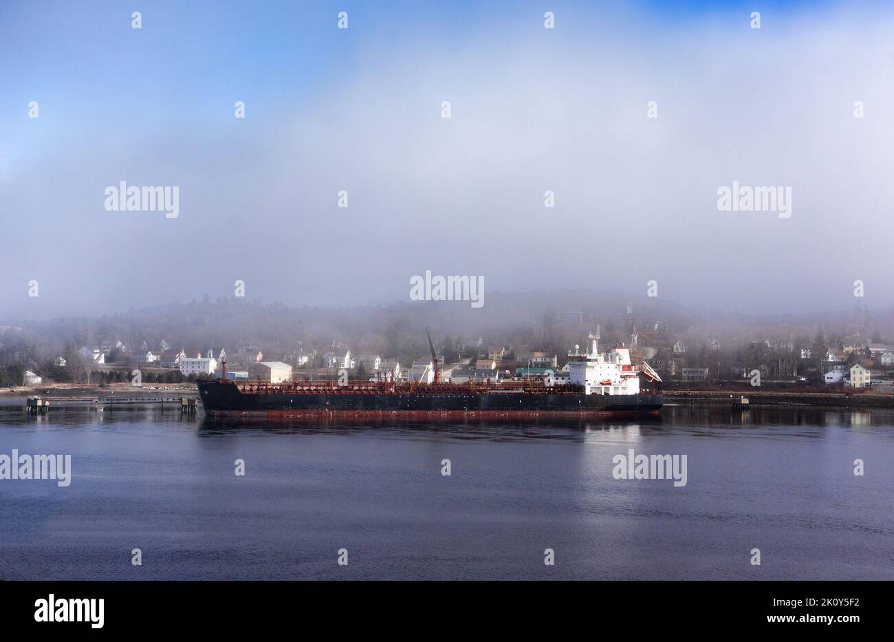 Ampia vista di una grande petroliera presso un molo commerciale nel Maine in una giornata di nebbia. Foto Stock