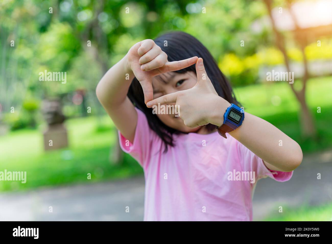 Primo piano della bambina sorridente che fa la cornice con le mani e le dita. Concetto di creatività e fotografia. Foto Stock