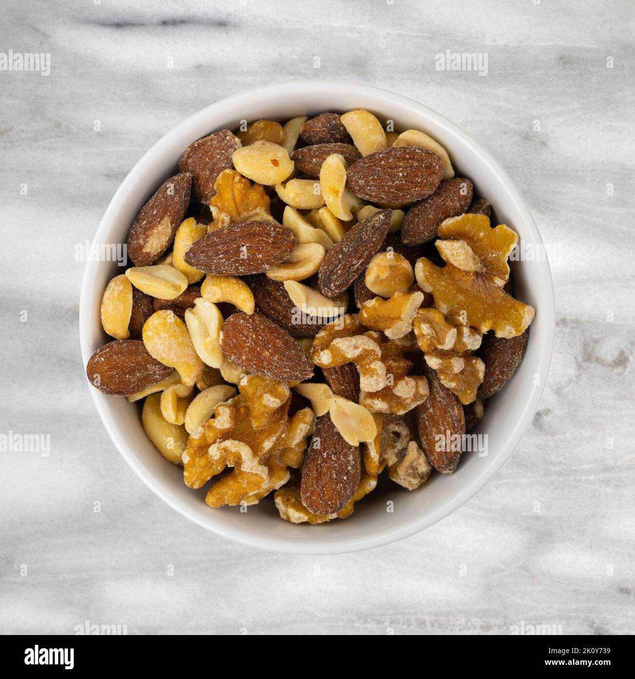 Dadi assortiti in una ciotola bianca sulla parte superiore di un tavolo in marmo grigio. Foto Stock