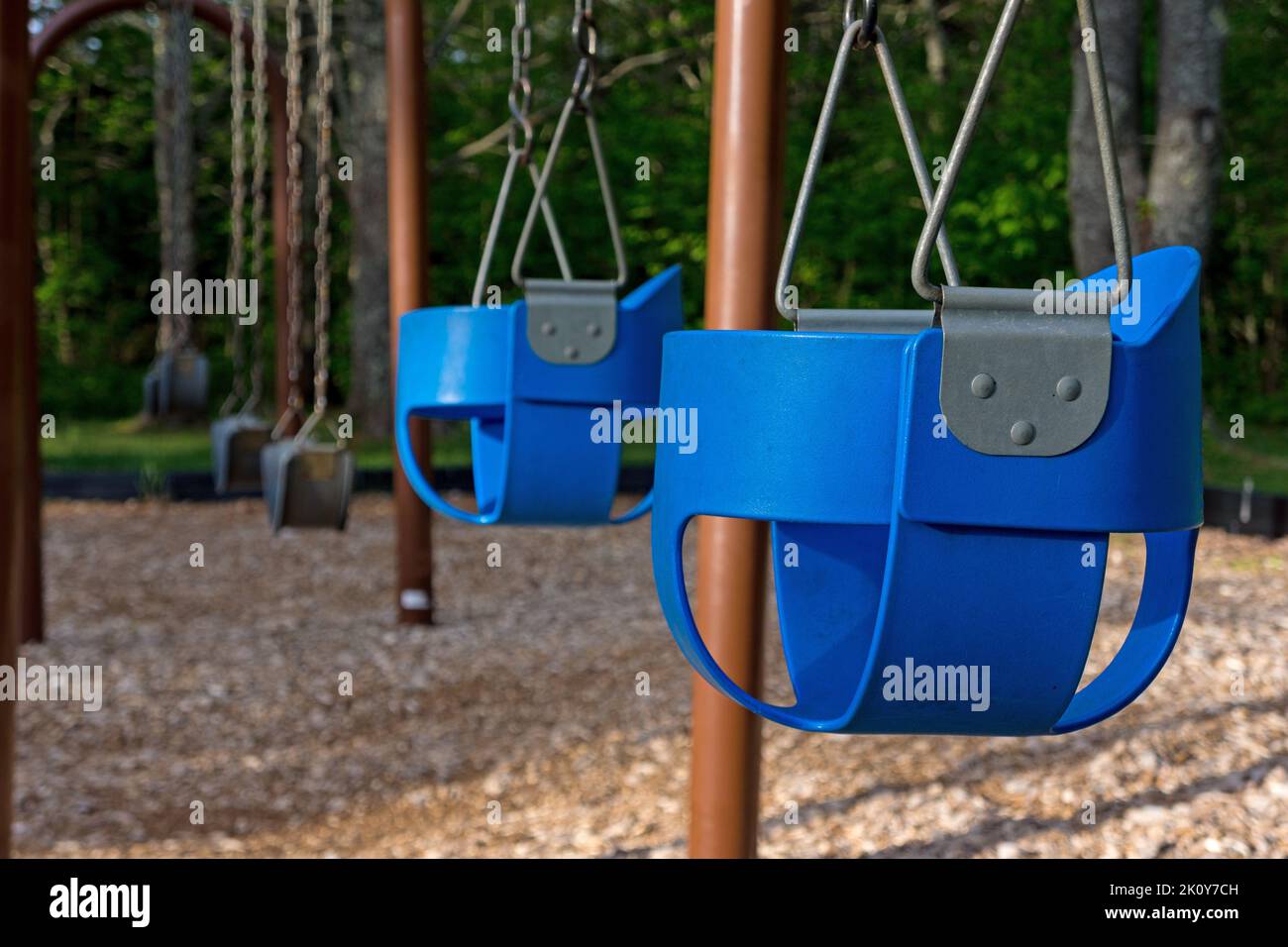 Parco giochi vuoto con altalene e seggiolini per bambini nella luce del mattino presto. Foto Stock