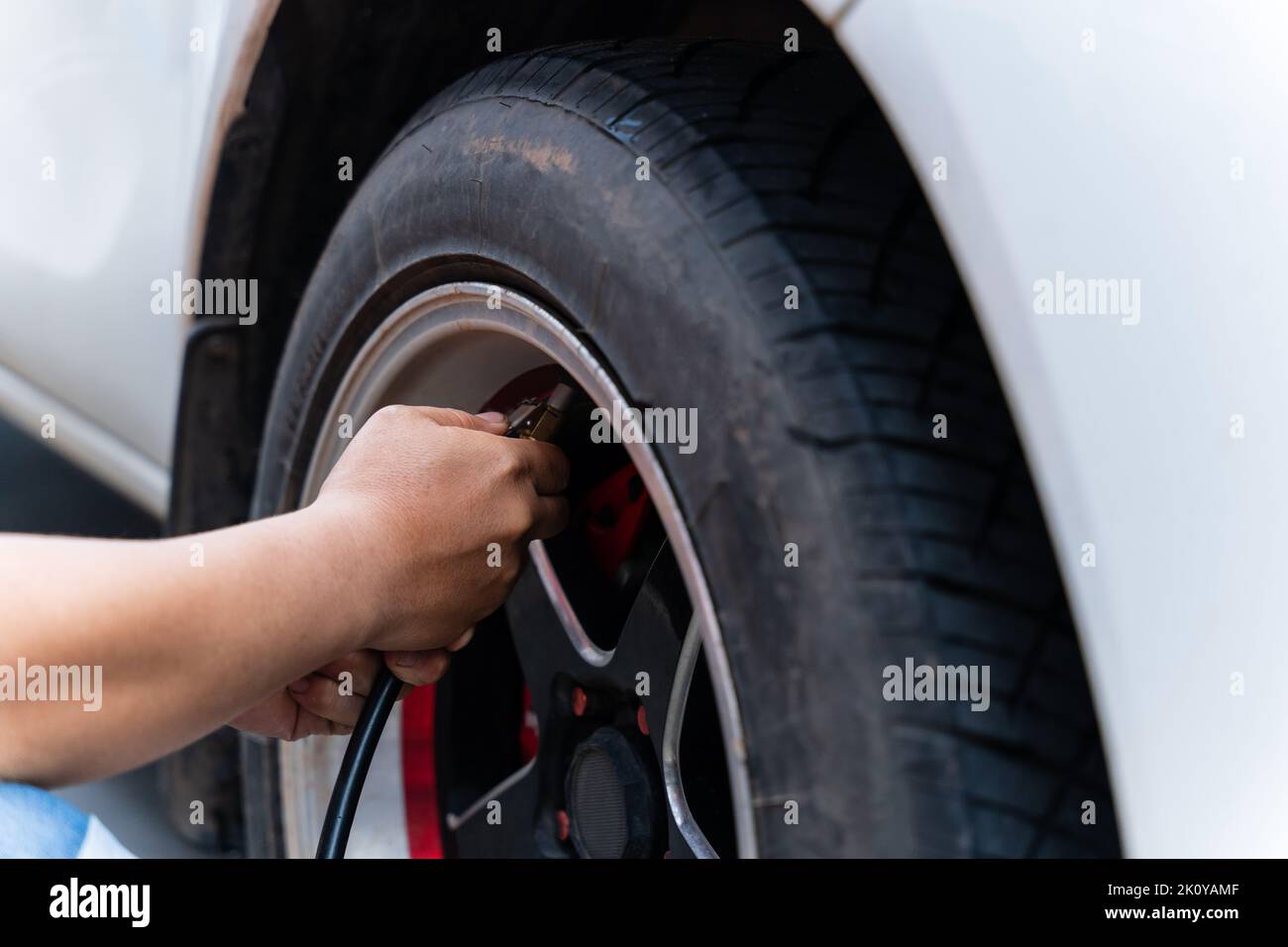 Primo piano di uomo che riempie aria negli pneumatici della sua auto. La mano e la ruota dell'auto aggiungono pressione dell'aria. Foto Stock