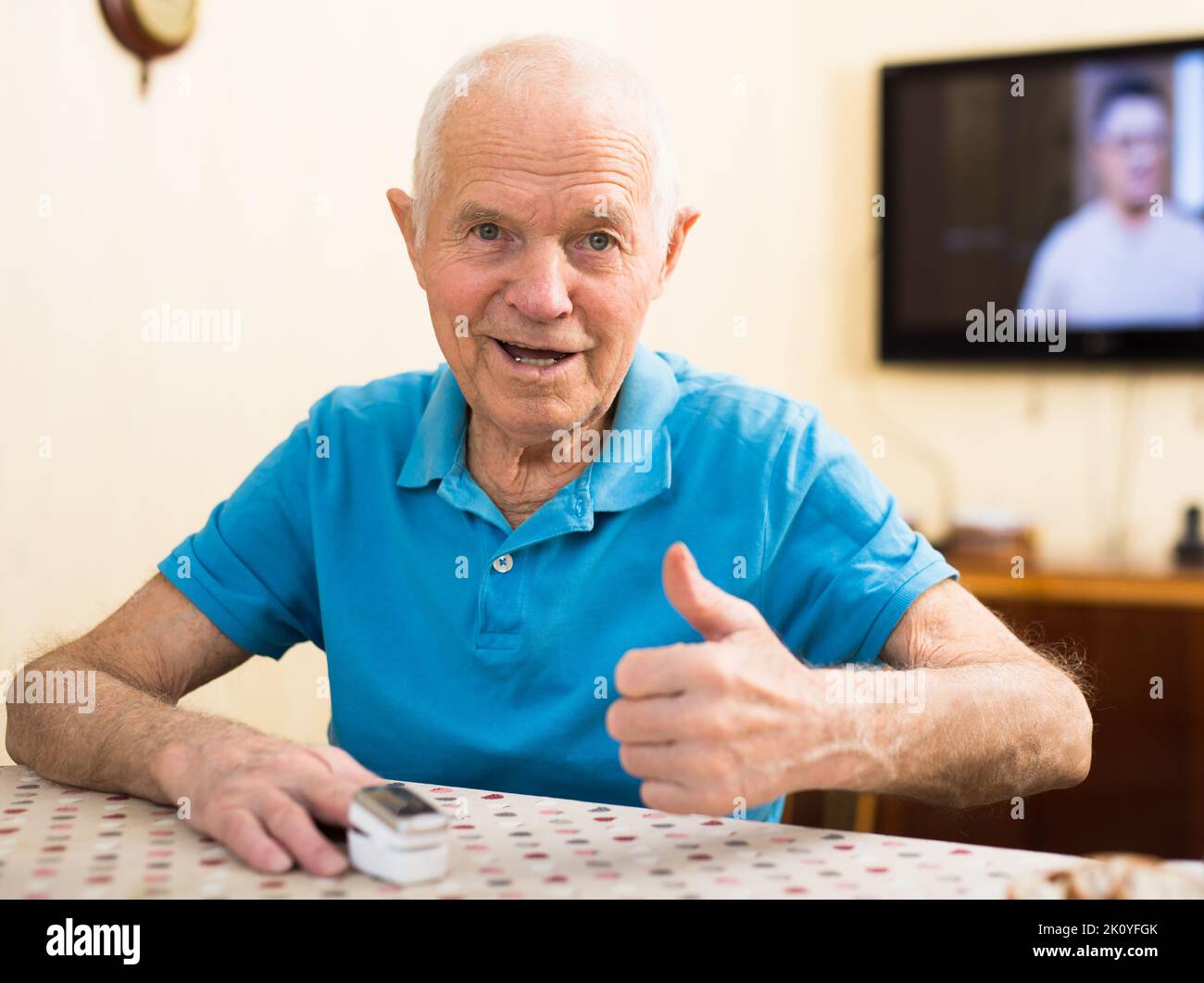 un uomo anziano seduto al tavolo di casa è felice di avere un buon umore Foto Stock
