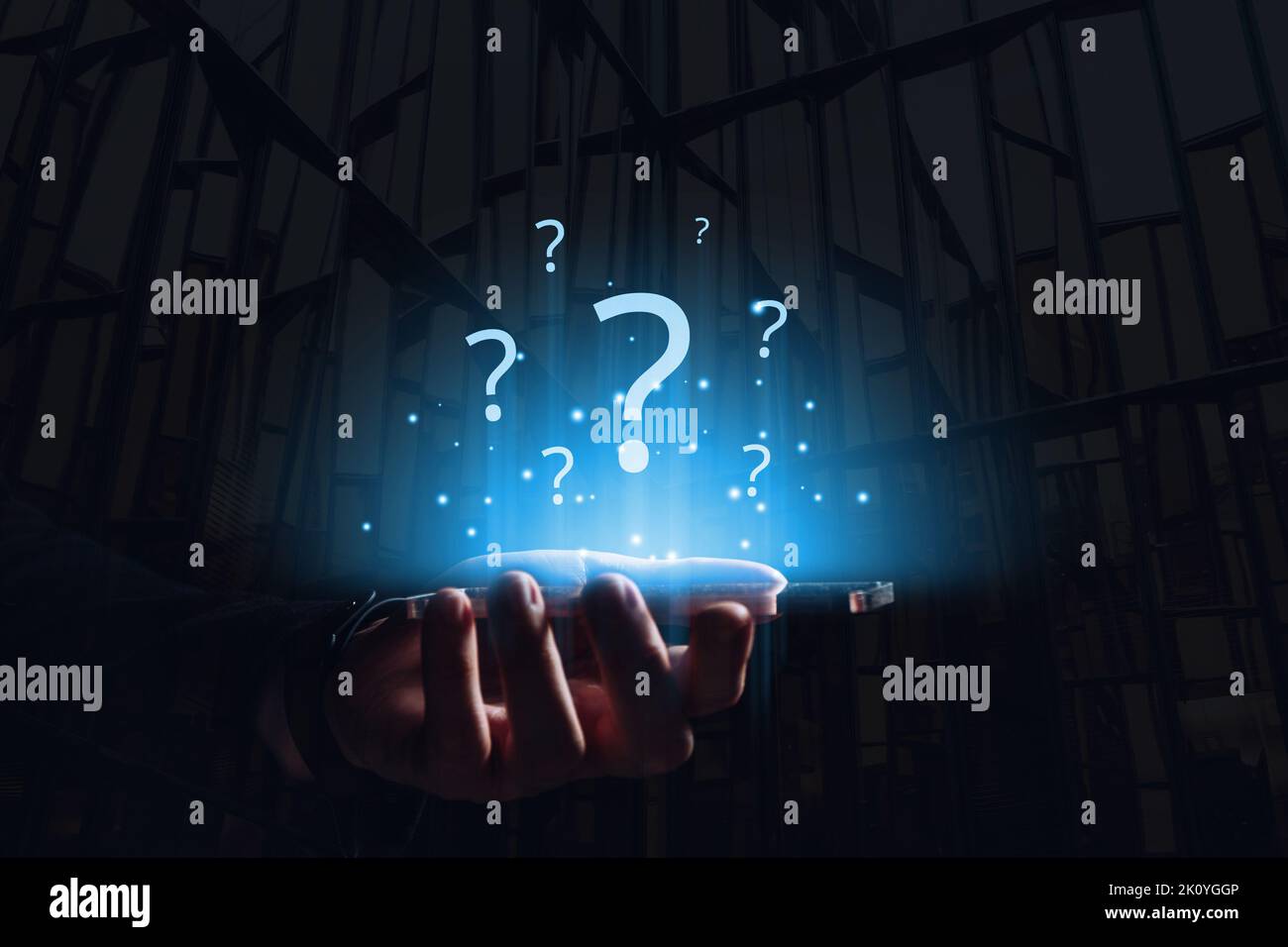 Molti punti interrogativi su un display olografico su un tablet nelle mani di una persona Foto Stock