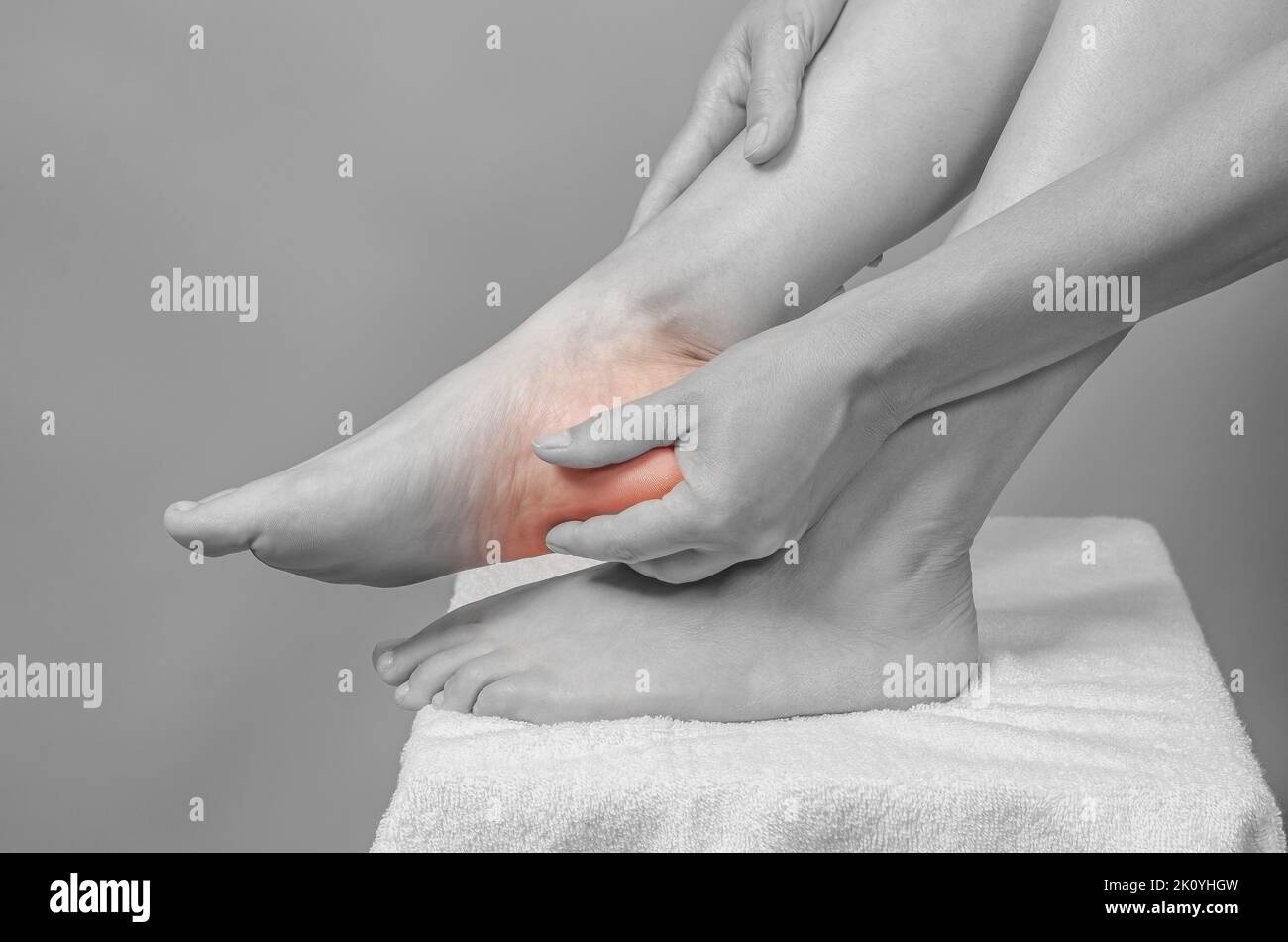 Vista dall'alto delle mani femminili che tengono il piede. Dolore ai piedi. Piedi femmina su asciugamano bianco. Foto Stock