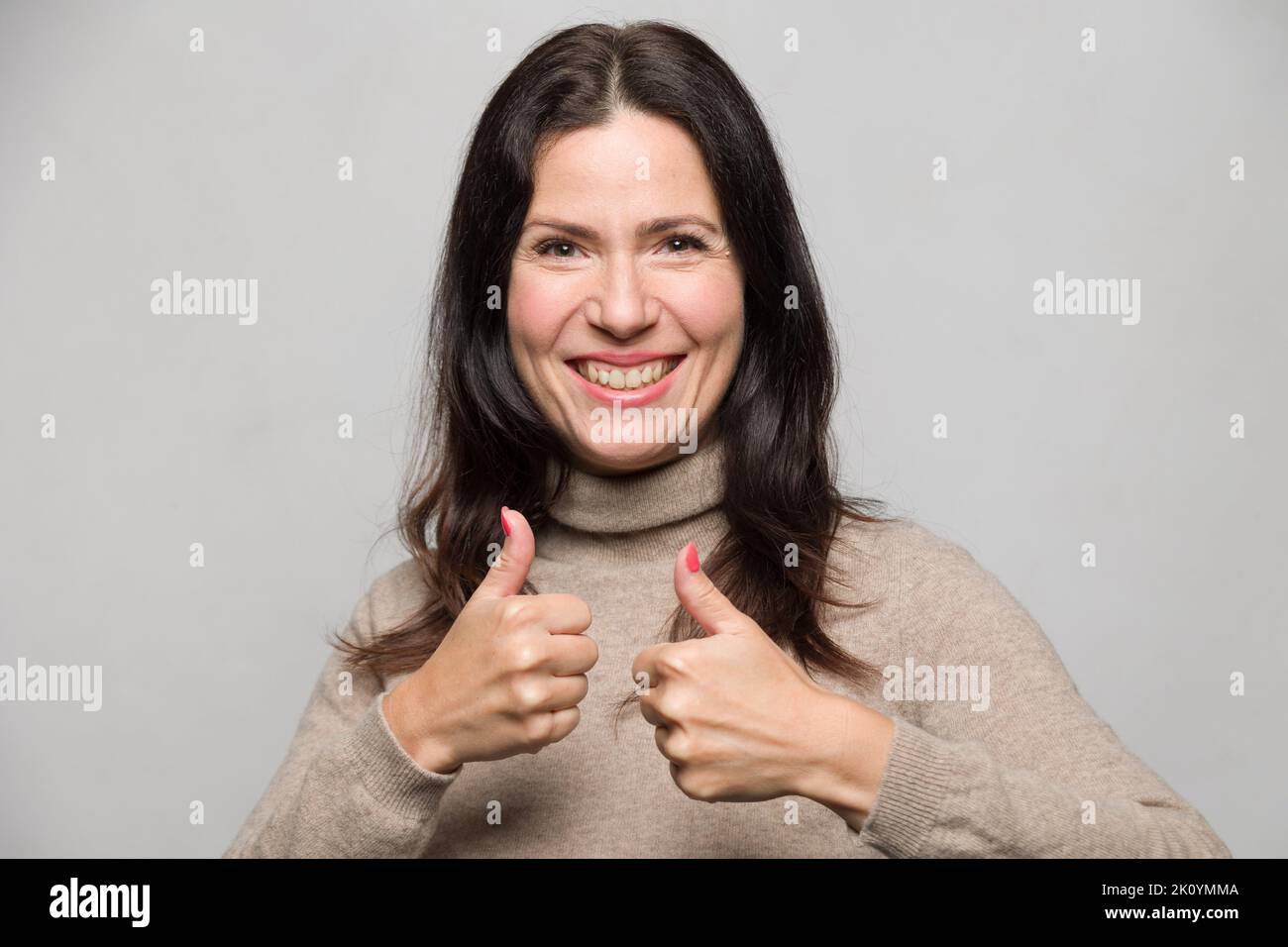 ritratto di una donna che mostra un gesto di pollice-su con entrambe le mani Foto Stock