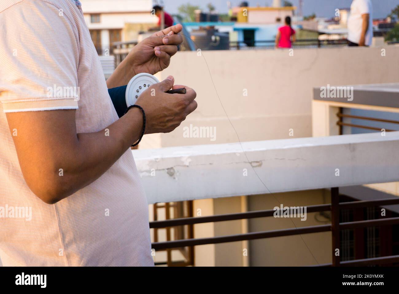 Un primo piano di un uomo con una bobina di aquilone con filo e manja colorata. India Foto Stock