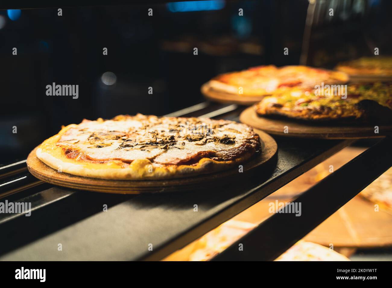 vista prospettica primo piano di diversi tipi di pizza su piatti di legno sugli scaffali della vetrina di street food Foto Stock