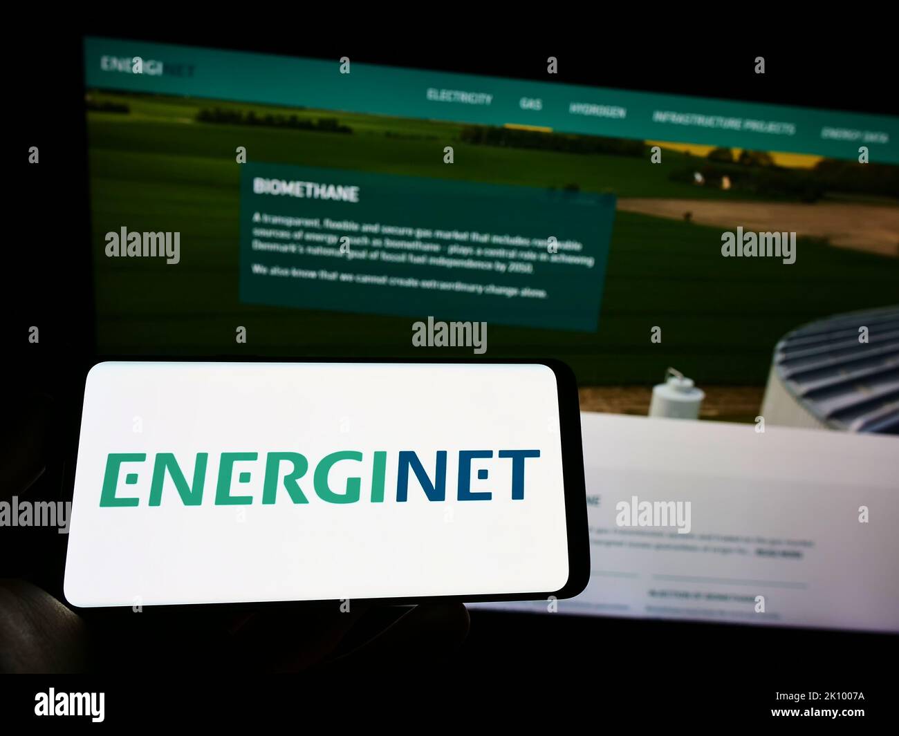 Persona che tiene il cellulare con il logo dell'operatore danese del sistema di trasmissione Energinet sullo schermo di fronte alla pagina web. Messa a fuoco sul display del telefono. Foto Stock