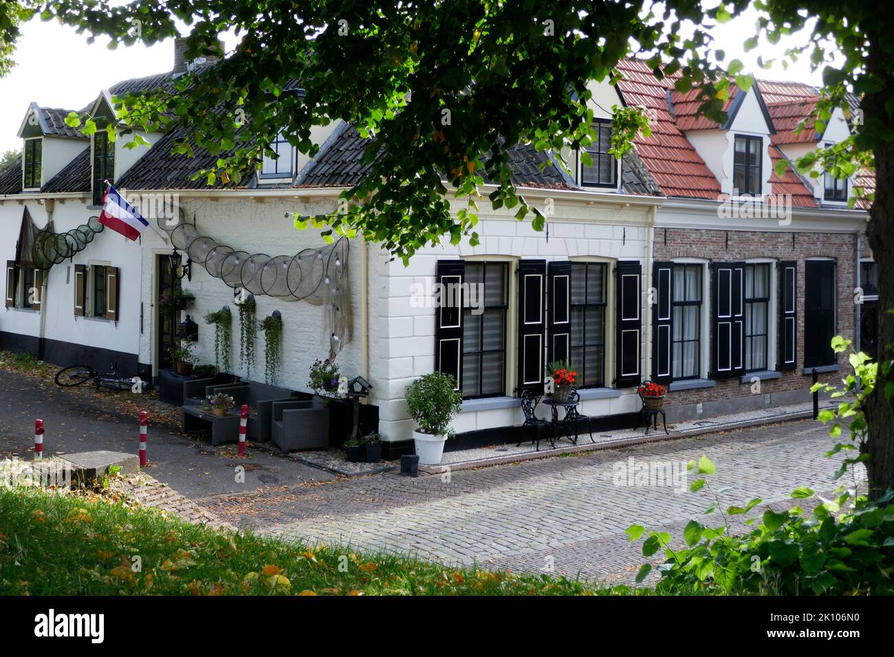 Tipiche case olandesi con tetti in tegole, porte nere e persiane alle finestre. Le reti da pesca mostrano che si tratta di un villaggio storico di pescatori. Foto Stock