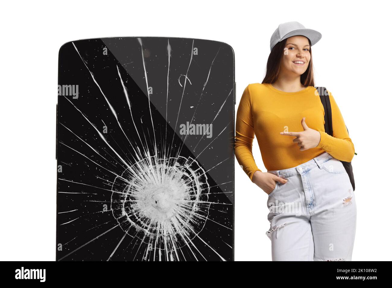 Giovane donna appoggiata su un telefono cellulare con schermo incrinato e puntando isolato su sfondo bianco Foto Stock