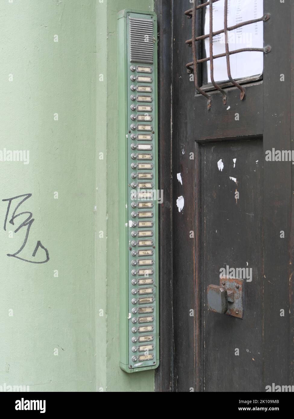 Una lunga barra di pulsanti del campanello con targhe su una porta vecchia Foto Stock