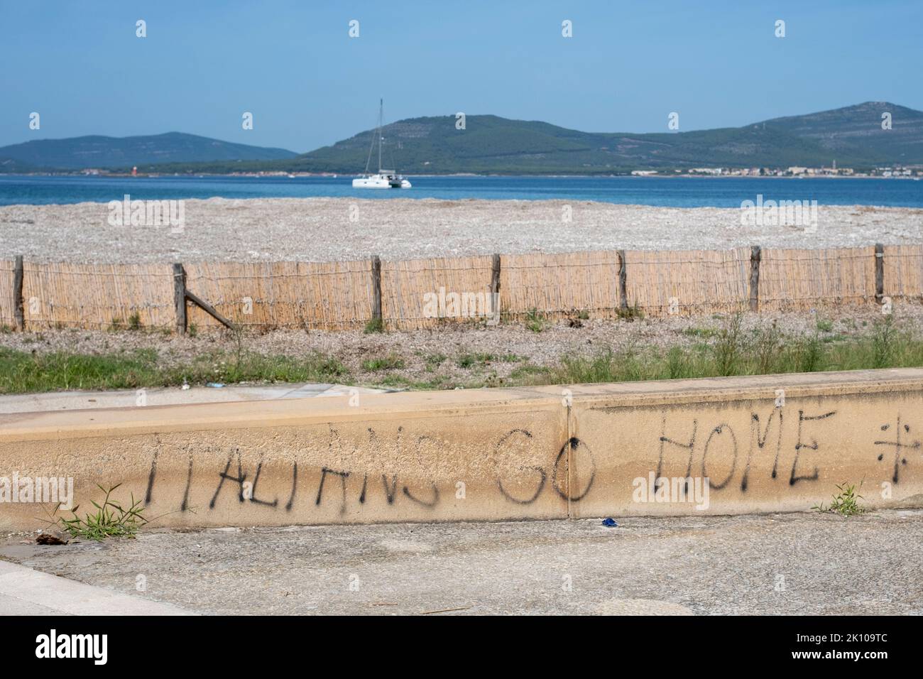 Italiani Vai Home graffiti Lungomare Promenade in Via Lido by Spiaggia del Lido in Alghero, Sardegna, Italia Foto Stock