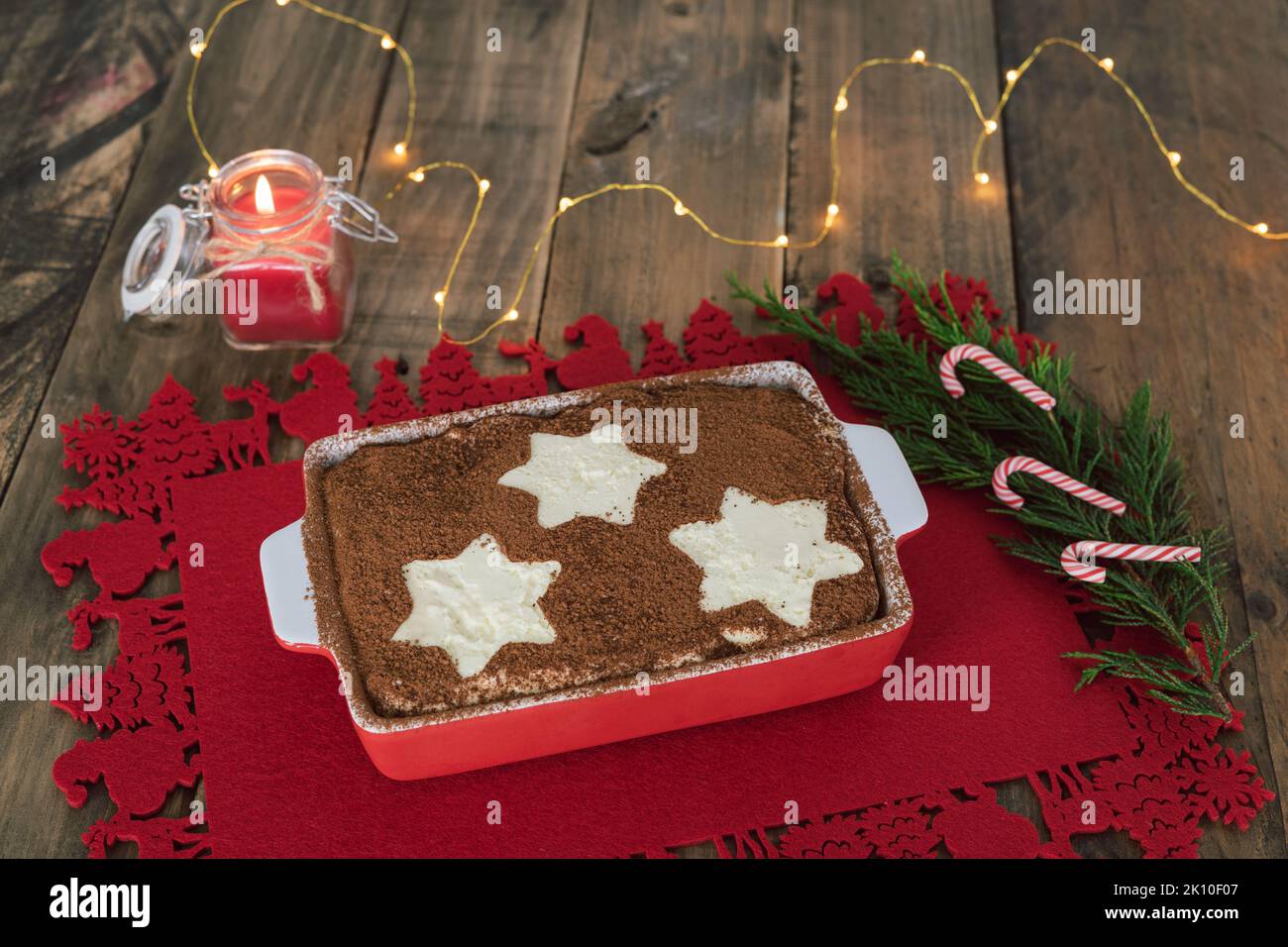 Tiramisù tradizionale dessert italiano con decorazione natalizia e candele e luci accese. Spazio di copia. Foto Stock