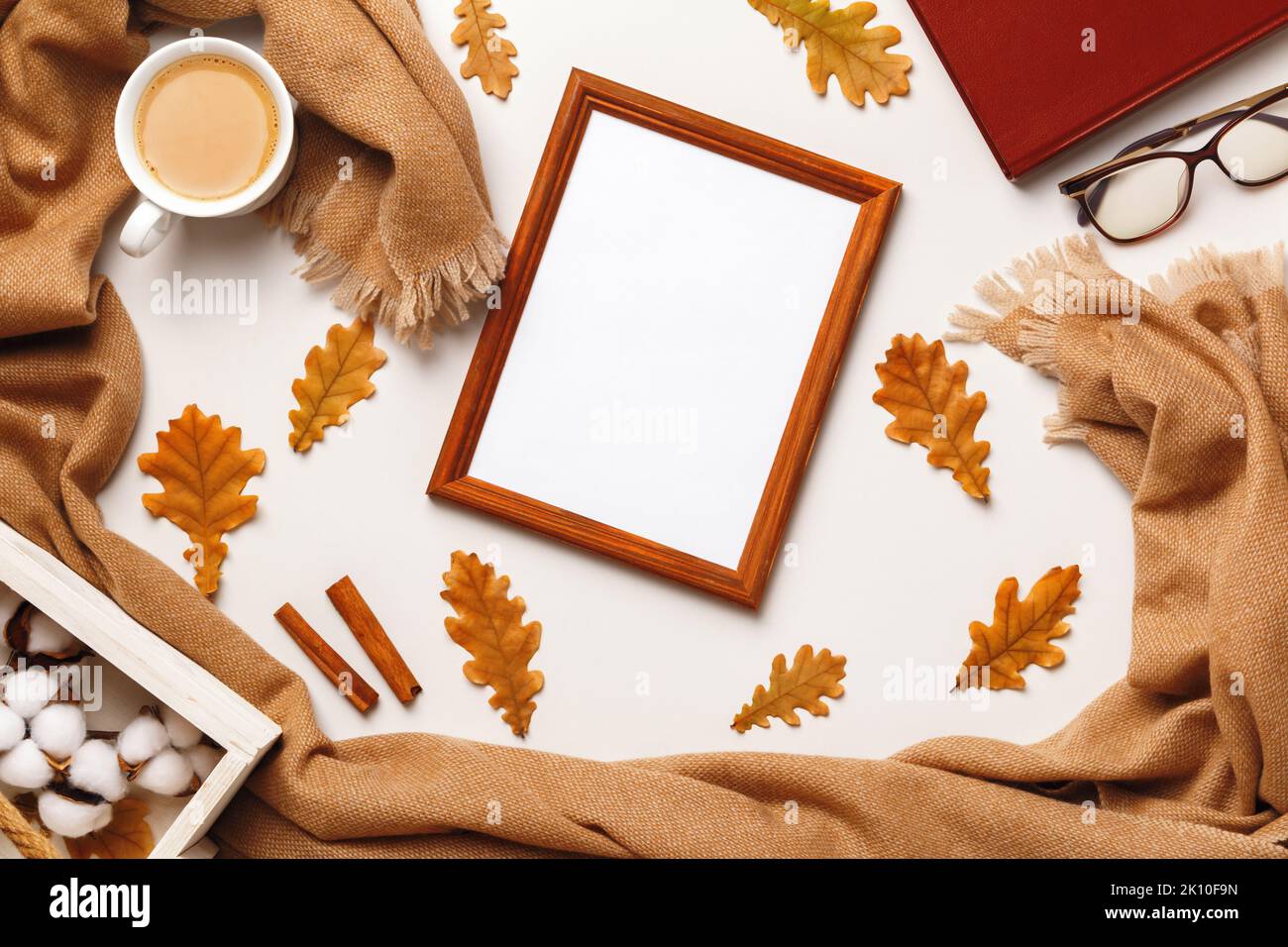 Concetto autunnale di comfort. Telaio in cashmere sciarpa bicchieri da libro caffè tazza con foglie. Foto Stock