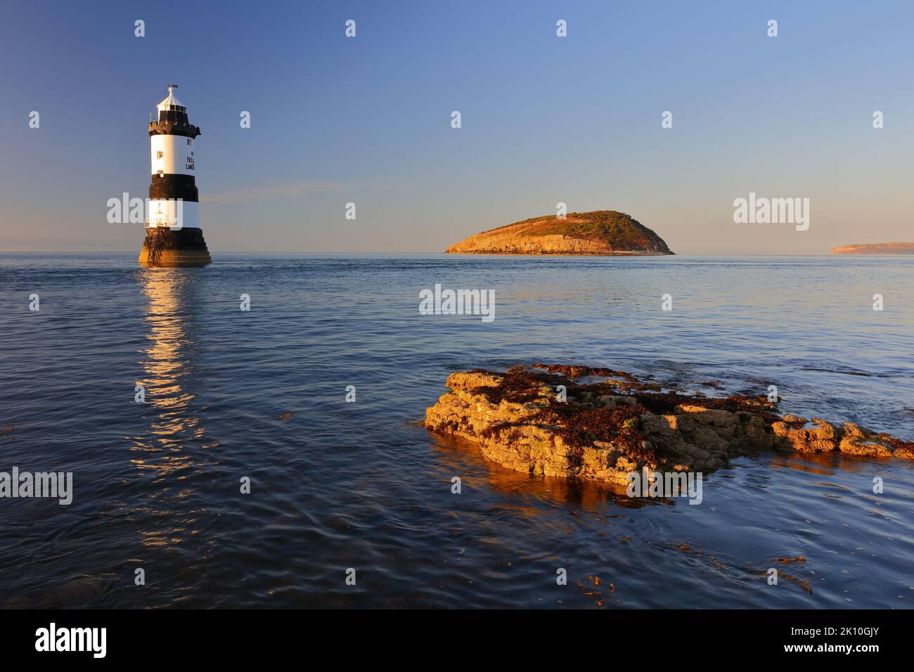 Penmon Lighthouse e Puffin Island in una tranquilla serata estiva. Anglesey, Galles del Nord, Regno Unito. Foto Stock