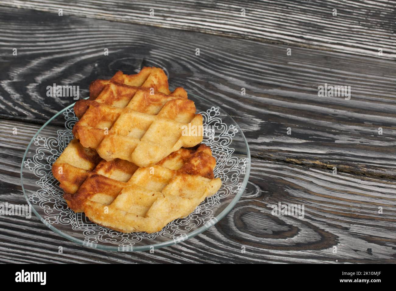 Soffici waffle. Giacciono su un piattino. Sfondo da tavole di pino nero. Primo piano. Foto Stock