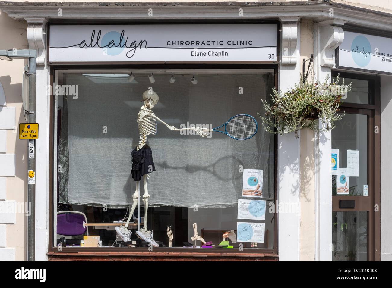 Chiropractic clinica stravagante vetrina negozio con uno scheletro in possesso di un racchetta da tennis, Liss, Hampshire, Inghilterra, Regno Unito Foto Stock