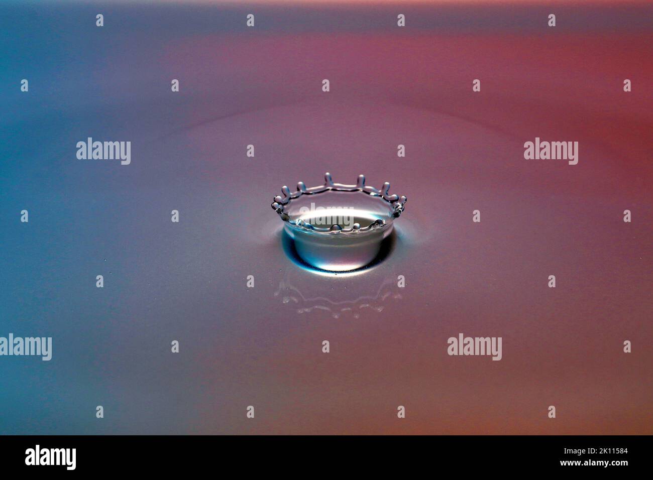Una goccia cade nell'acqua e crea grandi forme Foto Stock