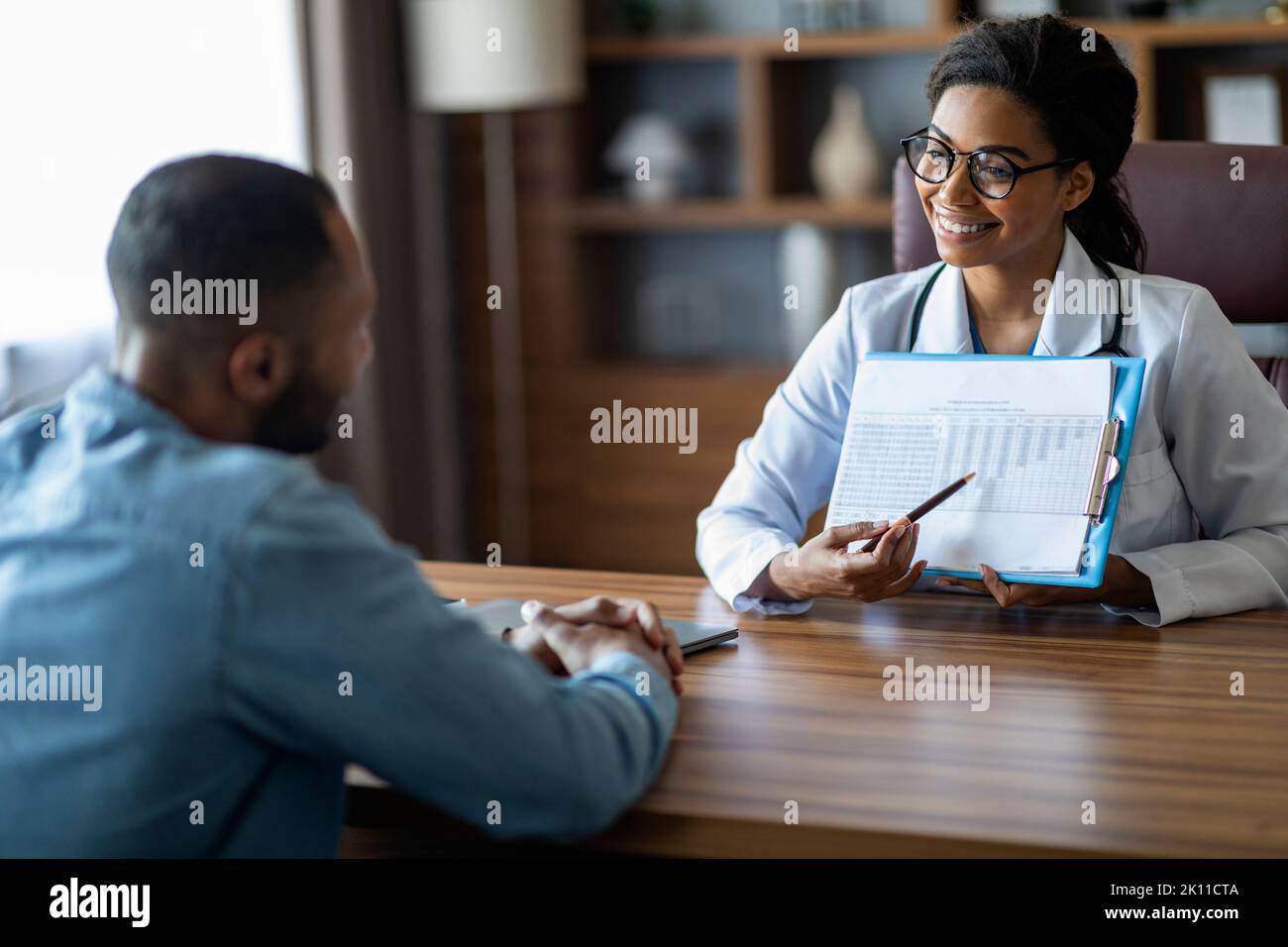 Allegro afro americano donna medico che mostra il piano di trattamento del paziente Foto Stock