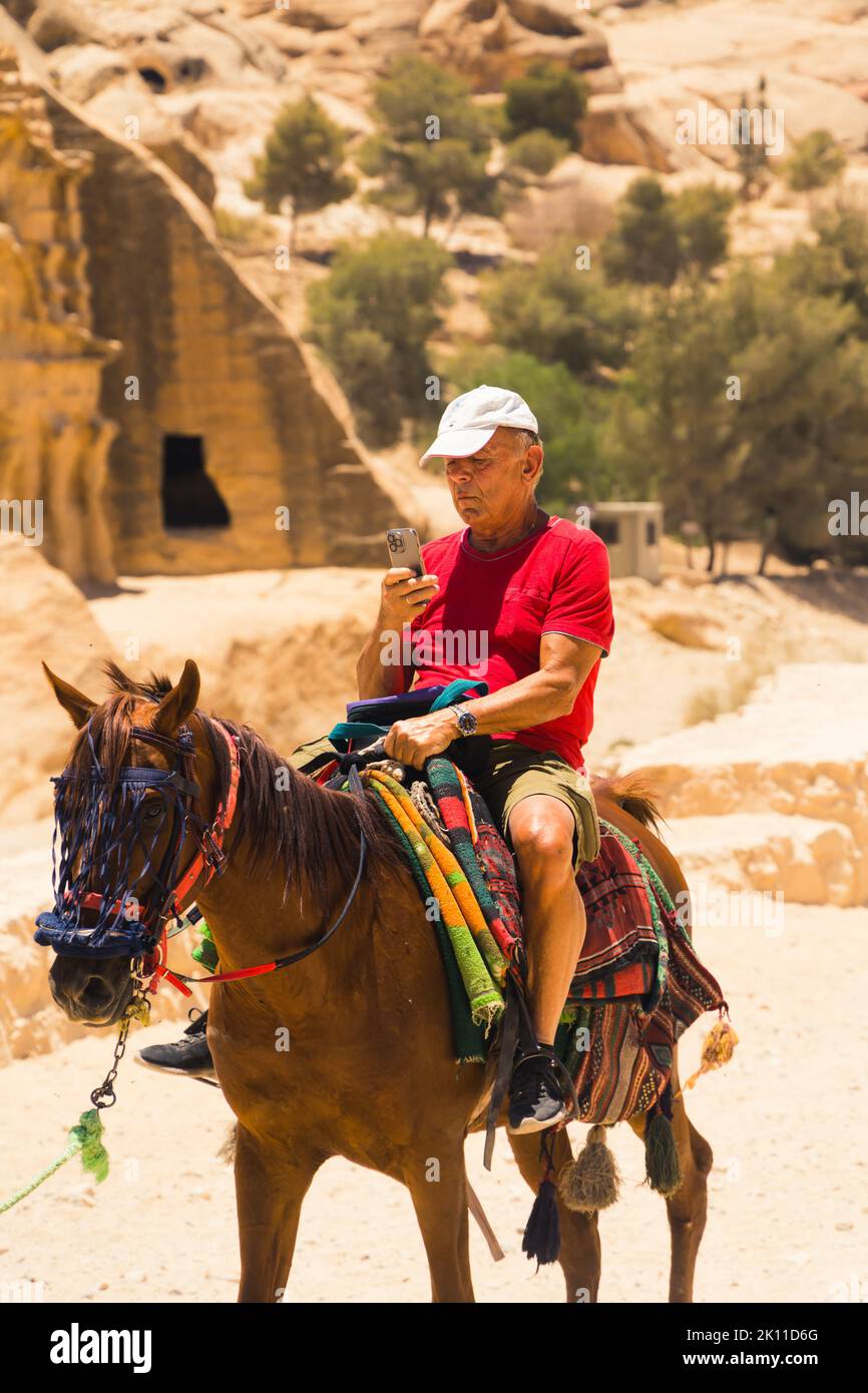 06.18.2022. Petra Canyon, Giordania. Un uomo che cavalca un cavallo e scatta foto con il suo cellulare. Foto di alta qualità Foto Stock