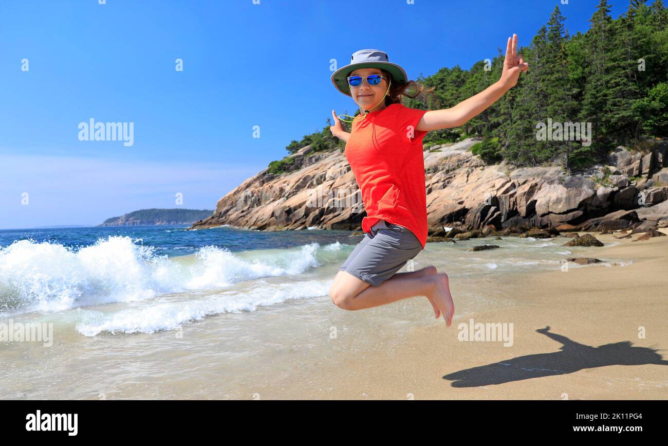 Ragazza giovane turista saltando su Sand Beach nel Parco Nazionale di Acadia, Maine, USA Foto Stock