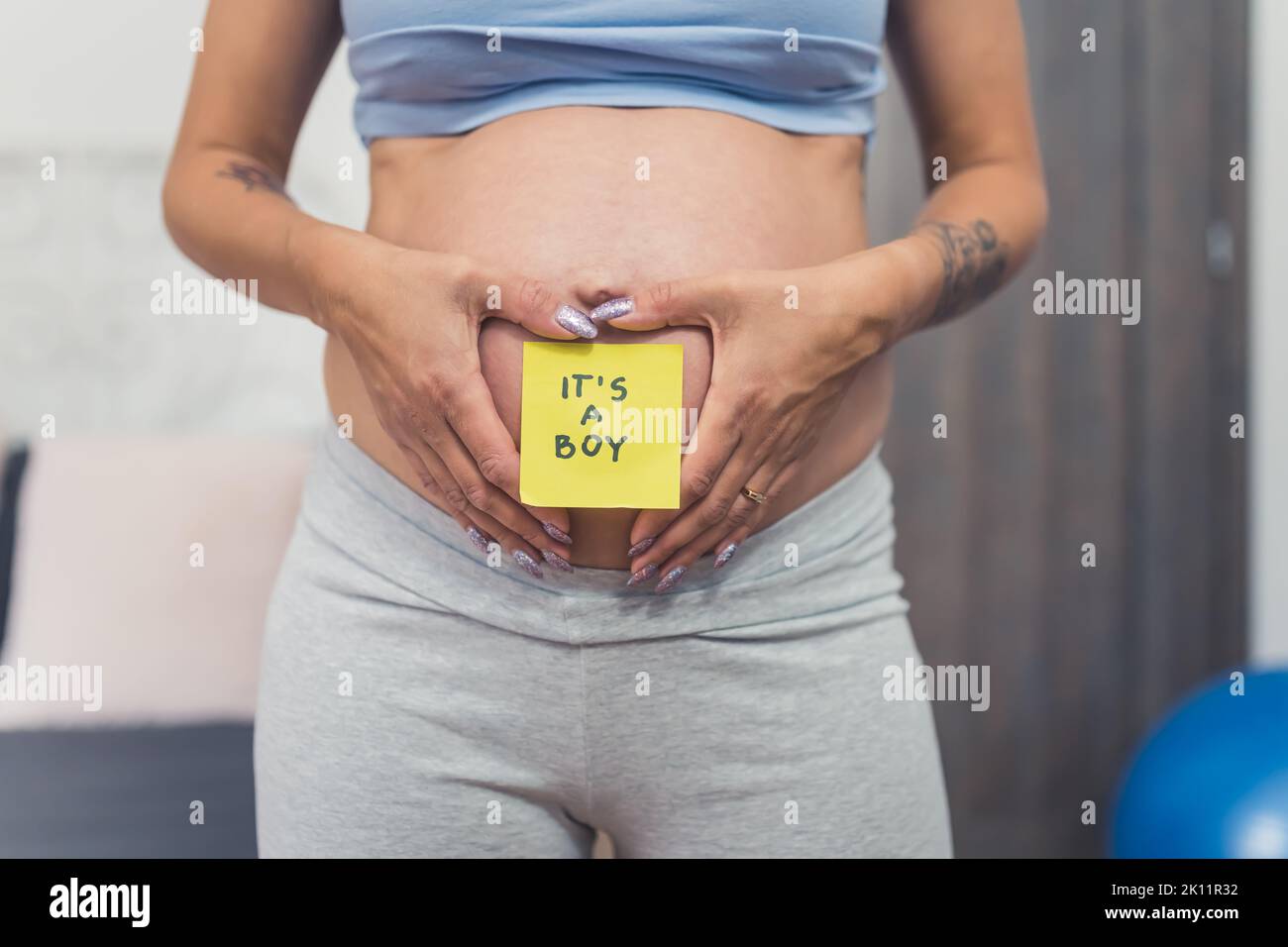 Donna incinta che tiene le mani intorno ad un adesivo sul suo ventre con la parola - ragazzo. Concetto di rivelazione di genere. Foto di alta qualità Foto Stock
