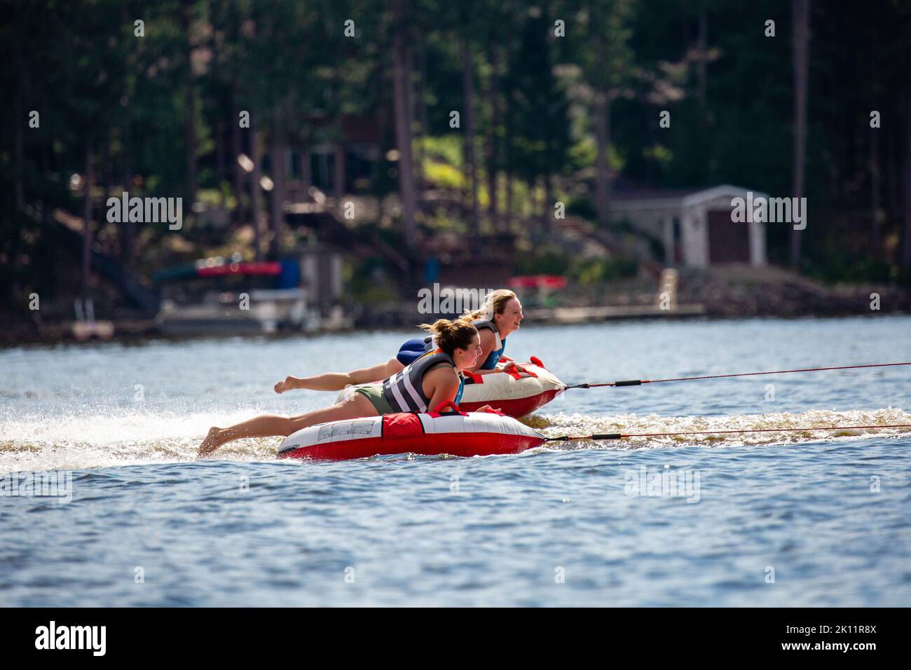 Lago Nokomis, Tomahawk, Wisconsin, Stati Uniti, agosto, 20, 2022 - le ragazze su un tubo gonfiabile che sono trainate attraverso il lago, orizzontale Foto Stock