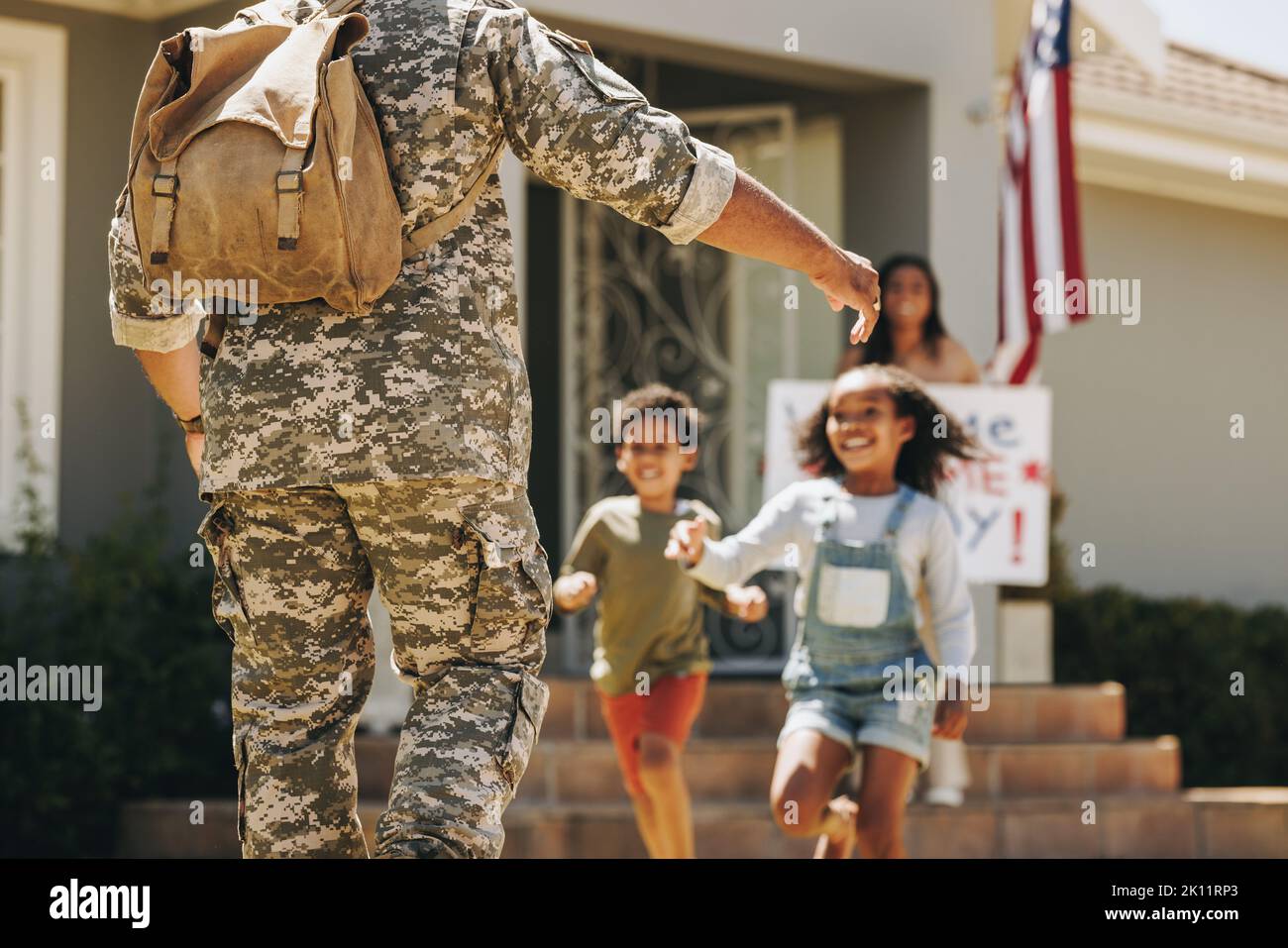 I bambini eccitati corrono per abbracciare il loro padre. Papà militare che riceve un caloroso benvenuto da sua moglie e i suoi figli a casa. Soldato americano di ritorno Foto Stock