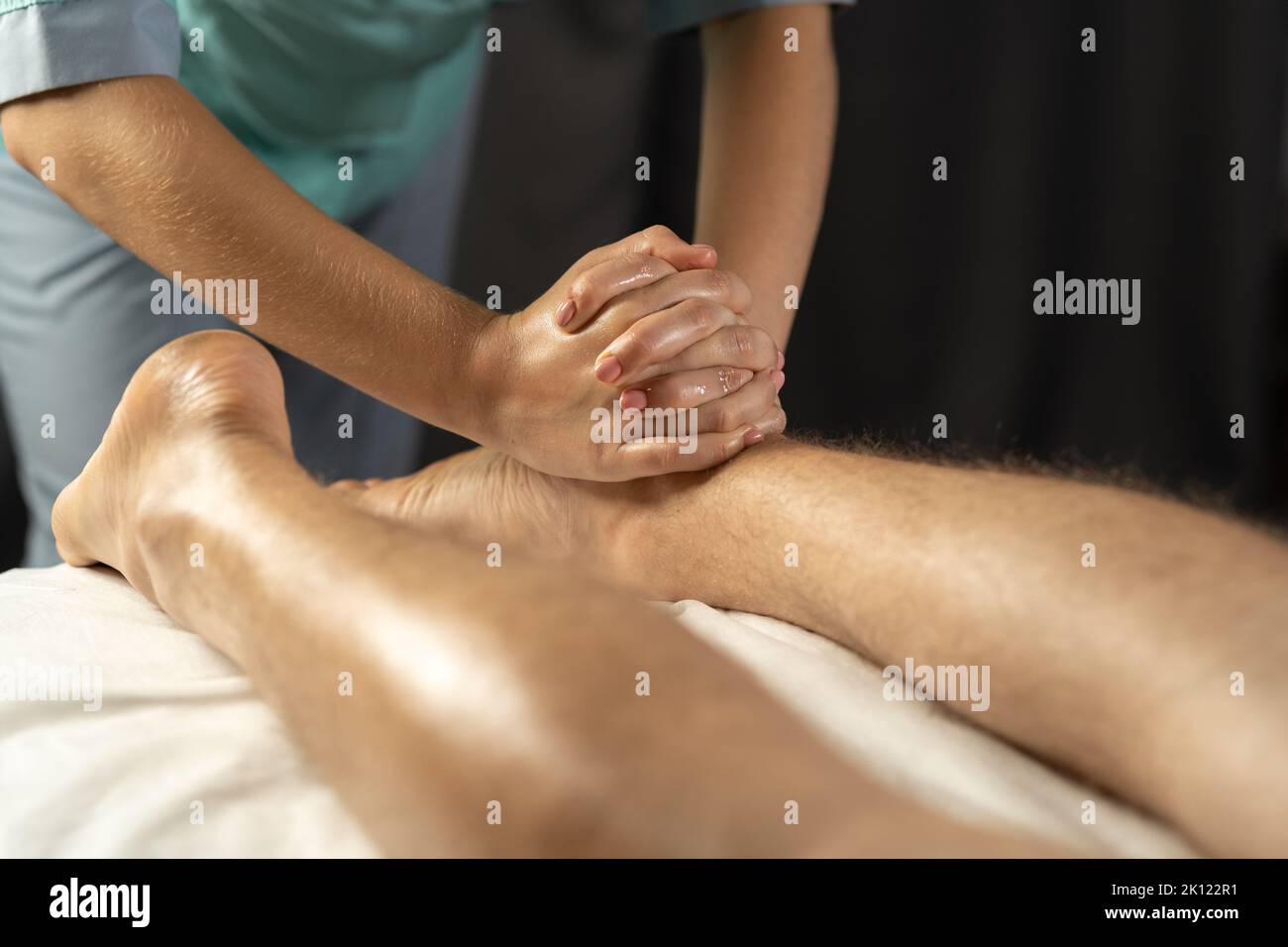 Concetto di massaggio sportivo. Massaggiatore femminile che lavora con un paziente massaggiando i vitelli. Foto Stock