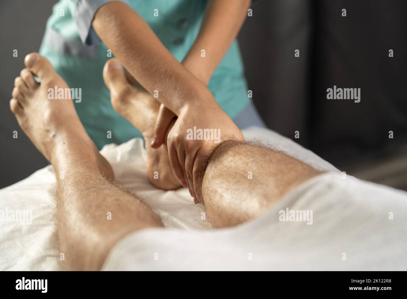 Massaggio ai piedi. Fisioterapista massaggiare le gambe di giovani atlete maschio in spa Foto Stock