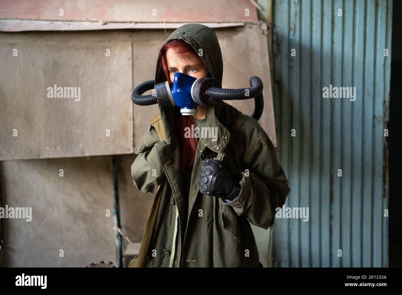 Sopravvivenza femminile post-apocalisse in maschera a gas su sfondo parete. Foto Stock