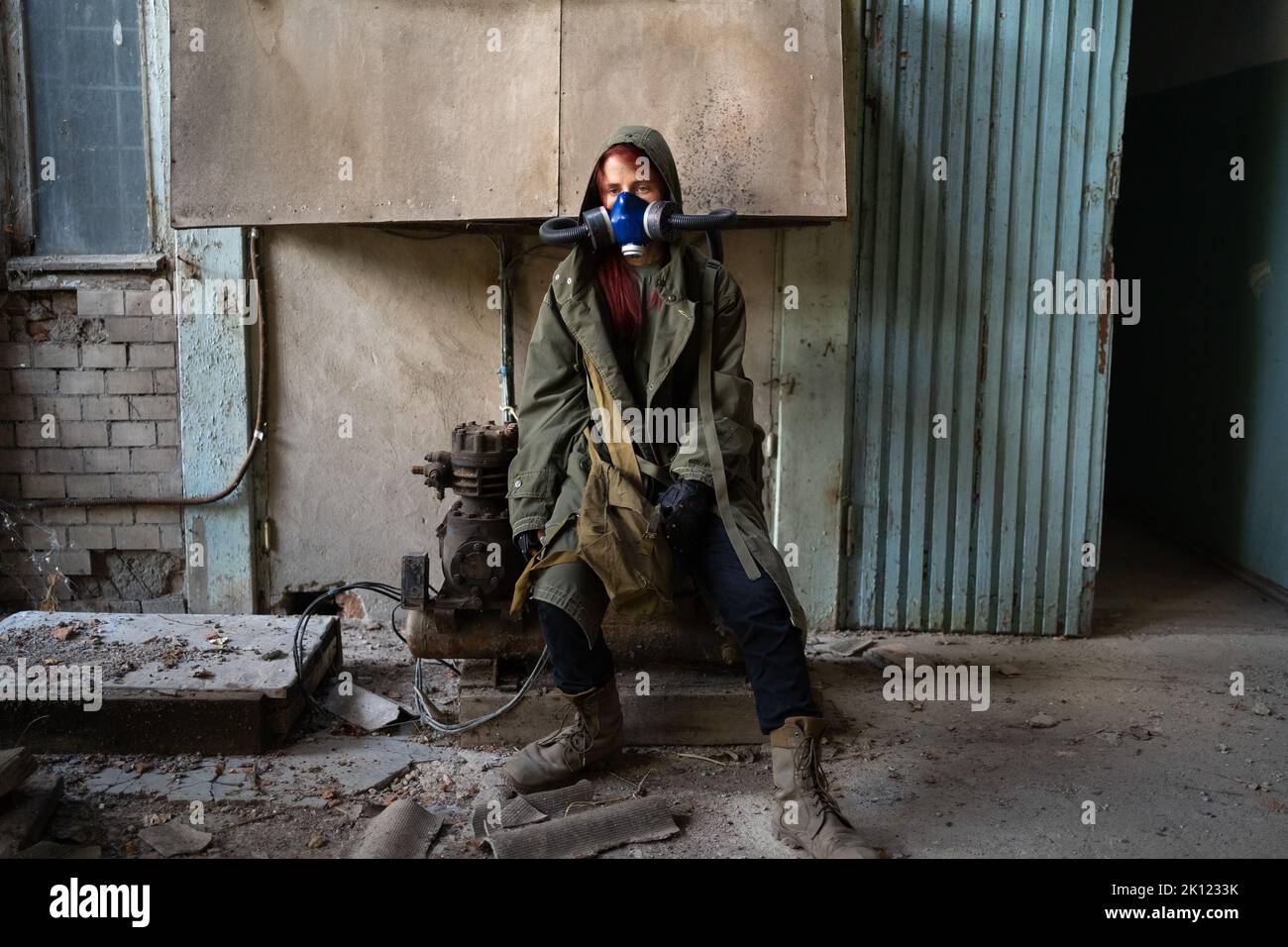 Sopravvissuta post apocalittica in maschera di gas, distrutto edificio sullo sfondo. Foto Stock