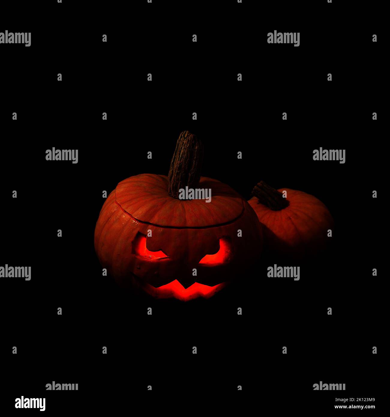 Lanterna di zucca di Halloween su sfondo scuro. Lampada spaventosa con occhi che si illuminano al buio. Foto Stock