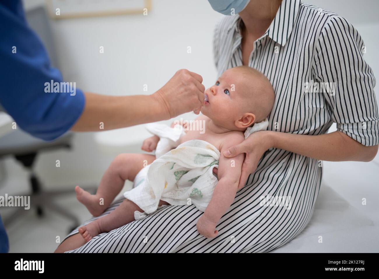 Il pediatra somministra la vaccinazione orale contro l'infezione da rotavirus al bambino piccolo in presenza di sua madre. Assistenza sanitaria e malattia dei bambini Foto Stock