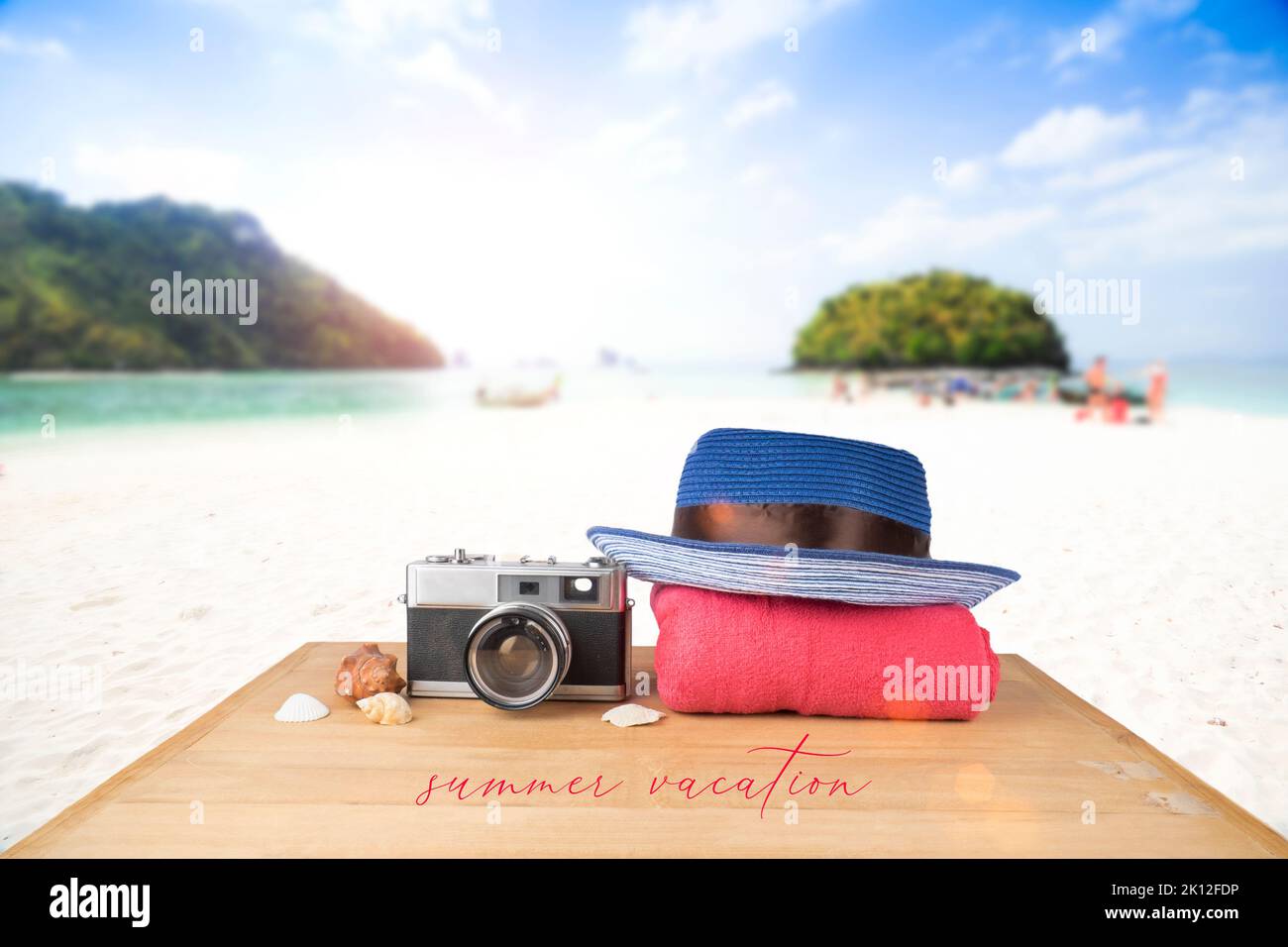 Concetto di idea. Torre rosa rossa, cappello blu, vecchia macchina fotografica vintage e conchiglie su pavimento in legno su cielo blu e sfondo oceano. Foto Stock