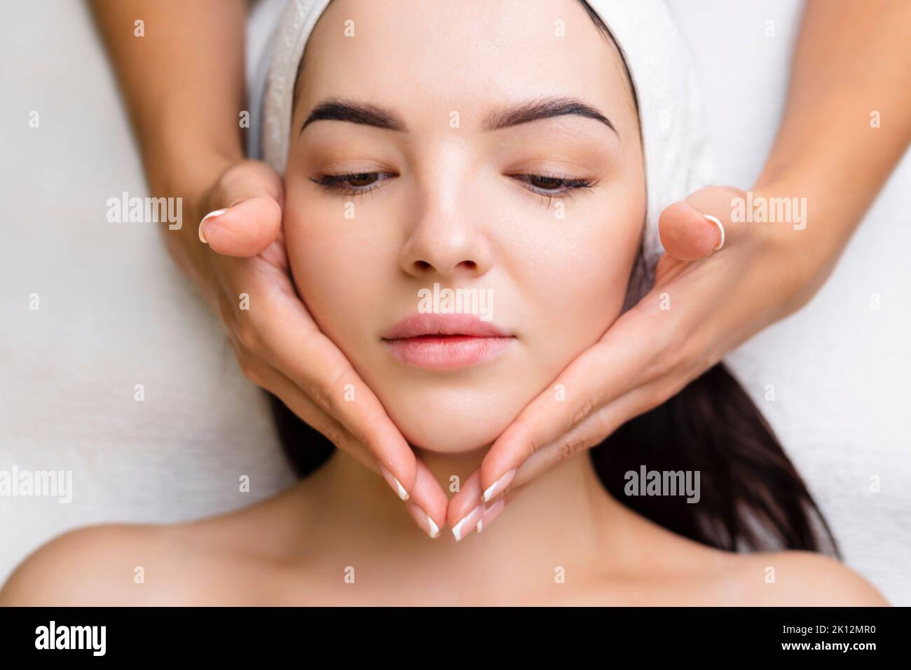 Massaggio professionale anti-invecchiamento del viso. Azione. Trattamento viso rilassante presso il centro benessere. Massaggio viso rilassante e rigenerante per le donne Foto Stock